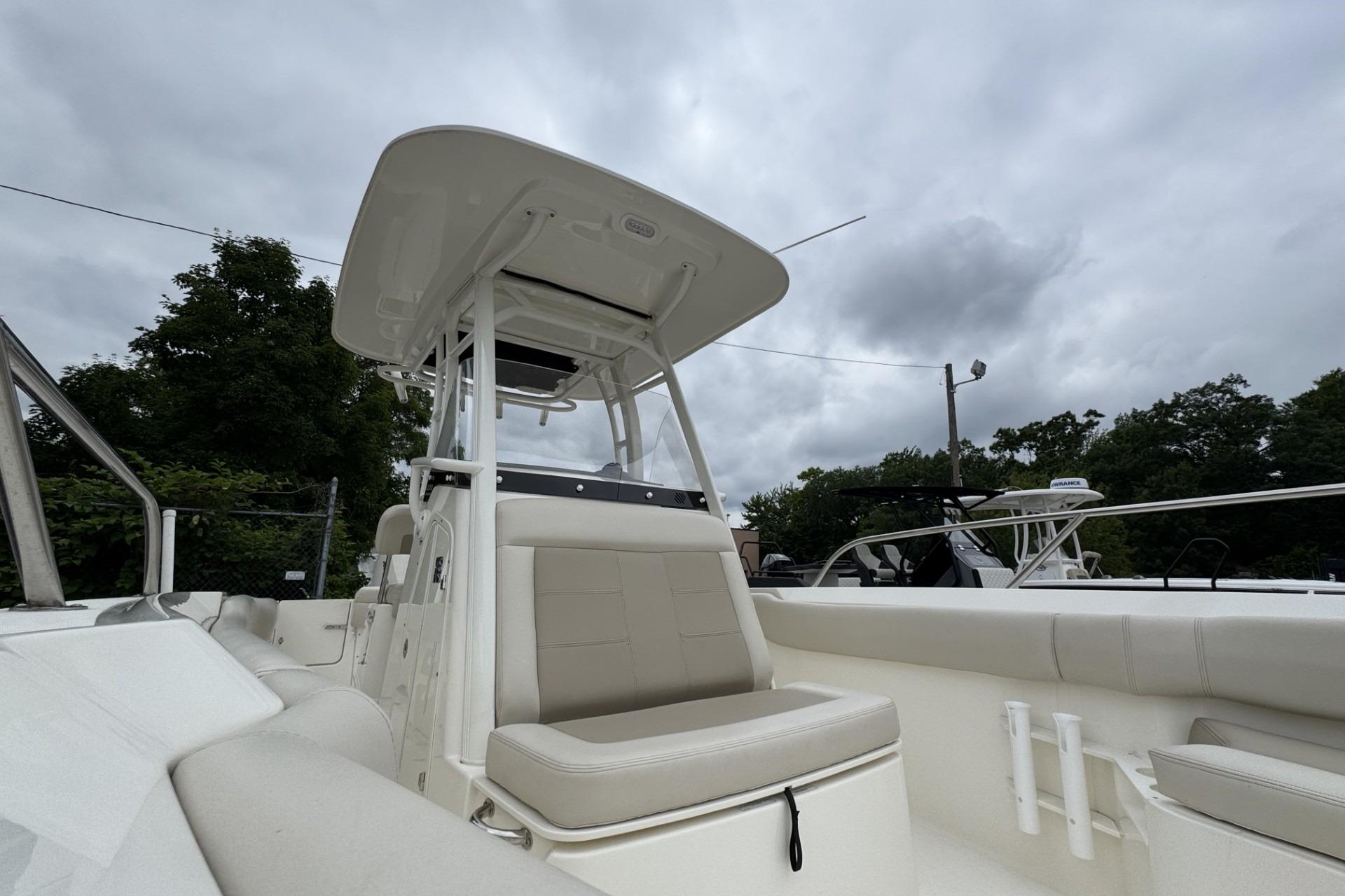 2024 Boston Whaler 230 Outrage boat with sleek seating and canopy under cloudy sky.