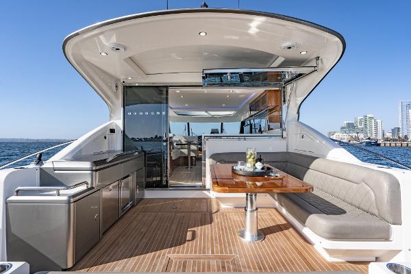 2021 Riviera 5400 Sport Yacht, spacious deck with seating and dining area, ocean view.