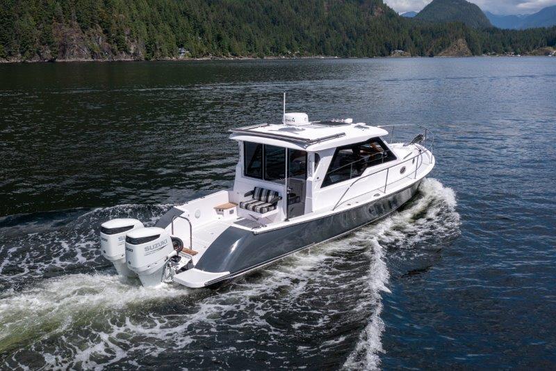 2024 True North 34 boat cruising on scenic lake with forested hills.