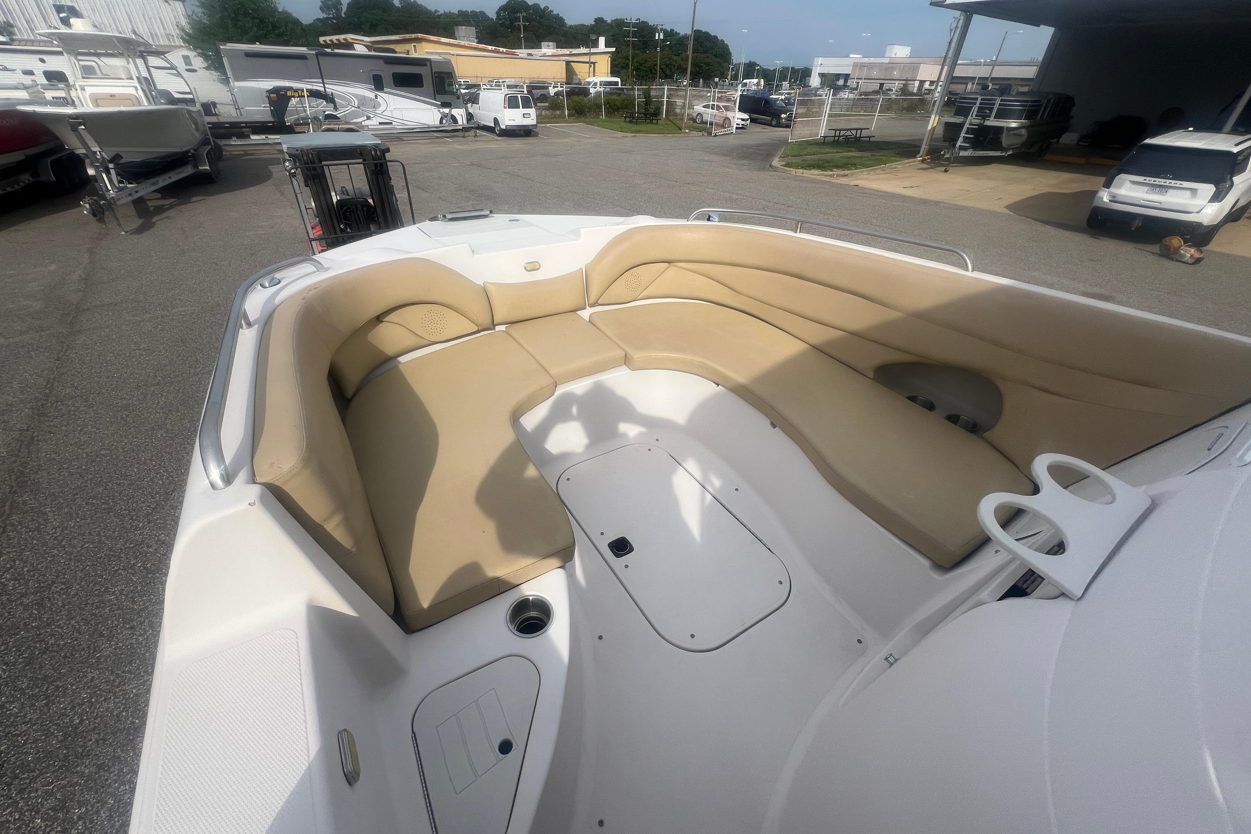 2002 Hurricane SunDeck 260 OB boat with beige seating, parked in a marina.