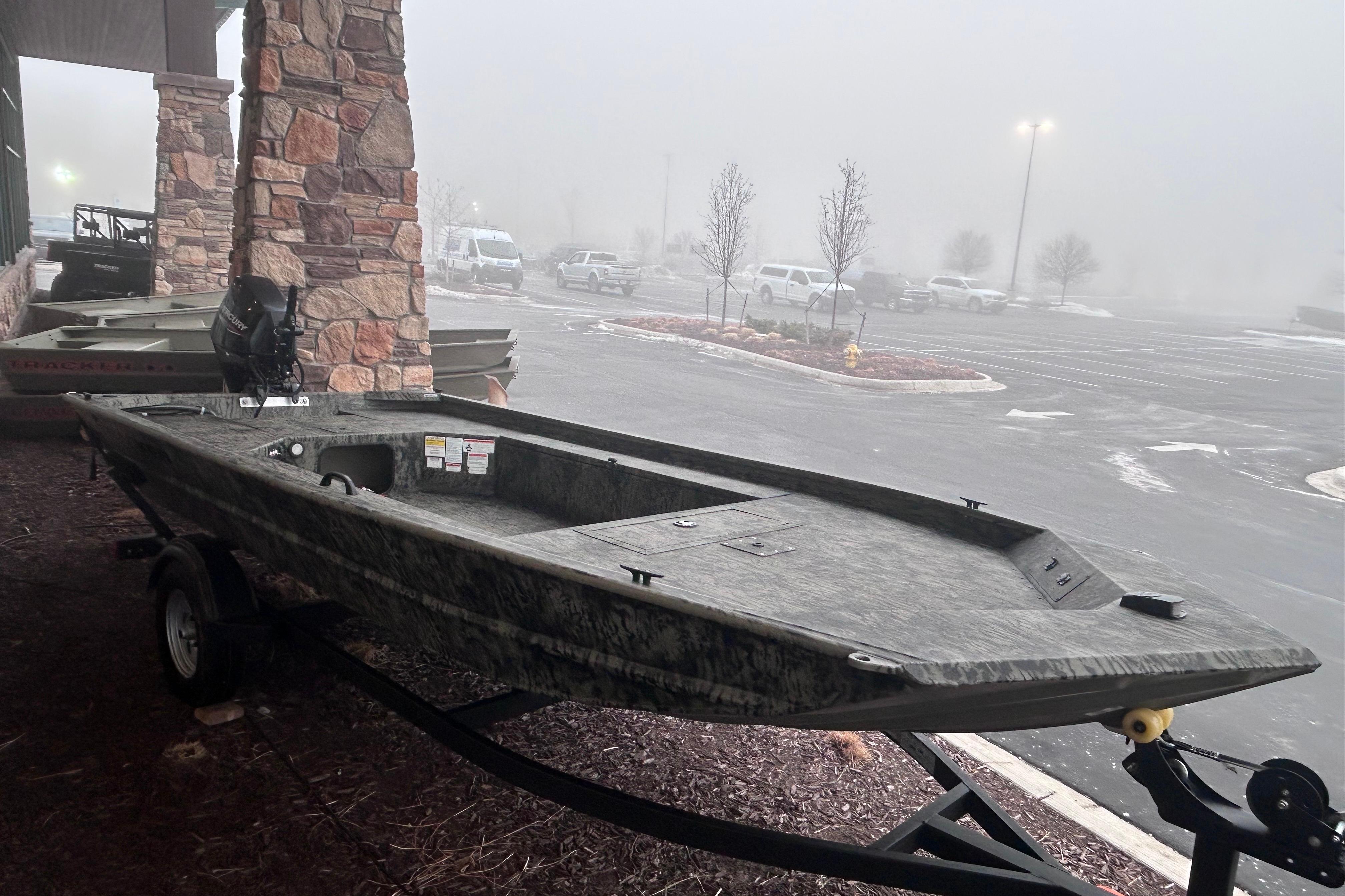 2026 Tracker Grizzly 1654 T Sportsman boat on trailer in foggy parking lot.