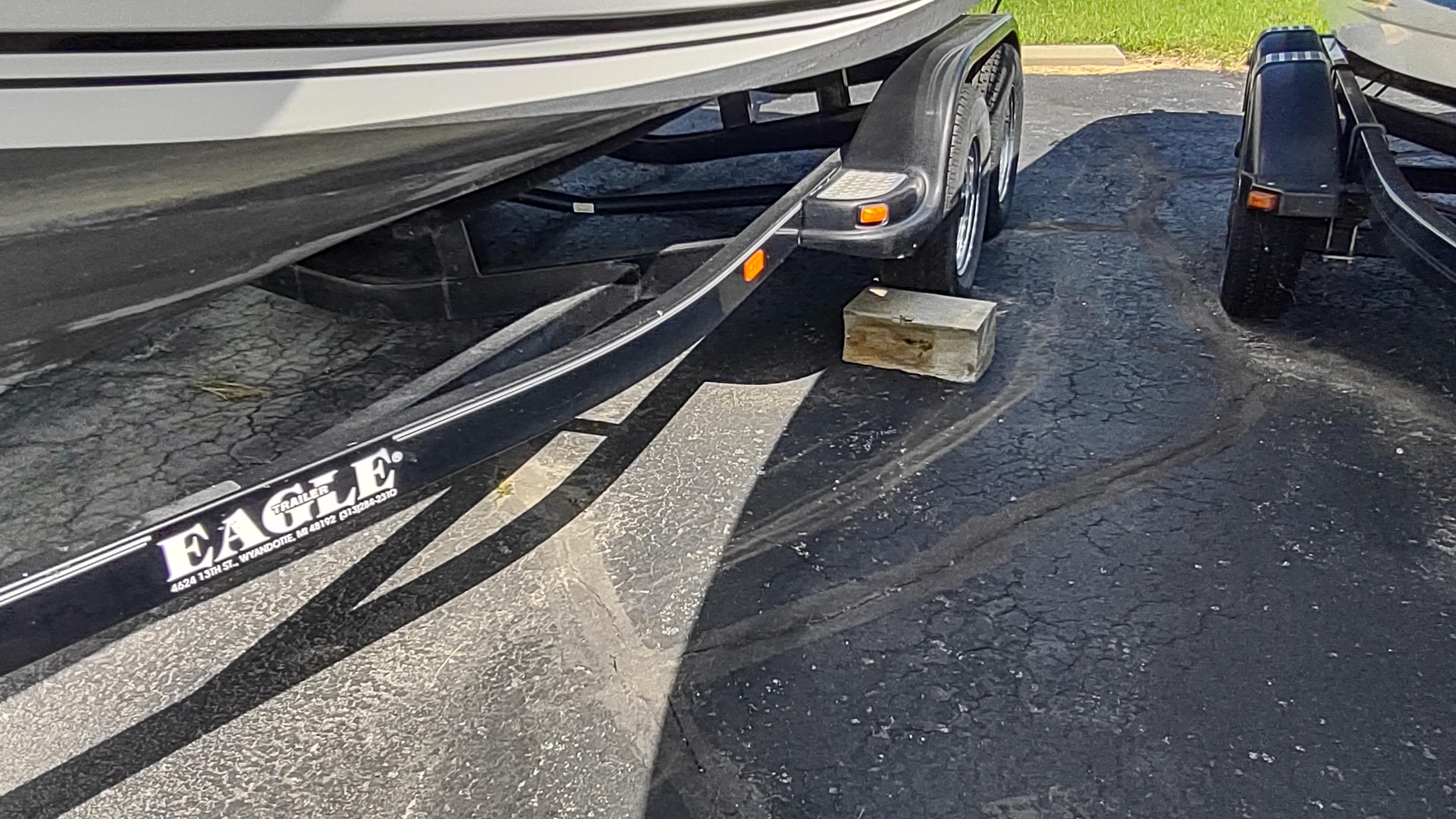 Robalo 2020 Center Console boat on Eagle trailer, parked on asphalt with wooden block support.