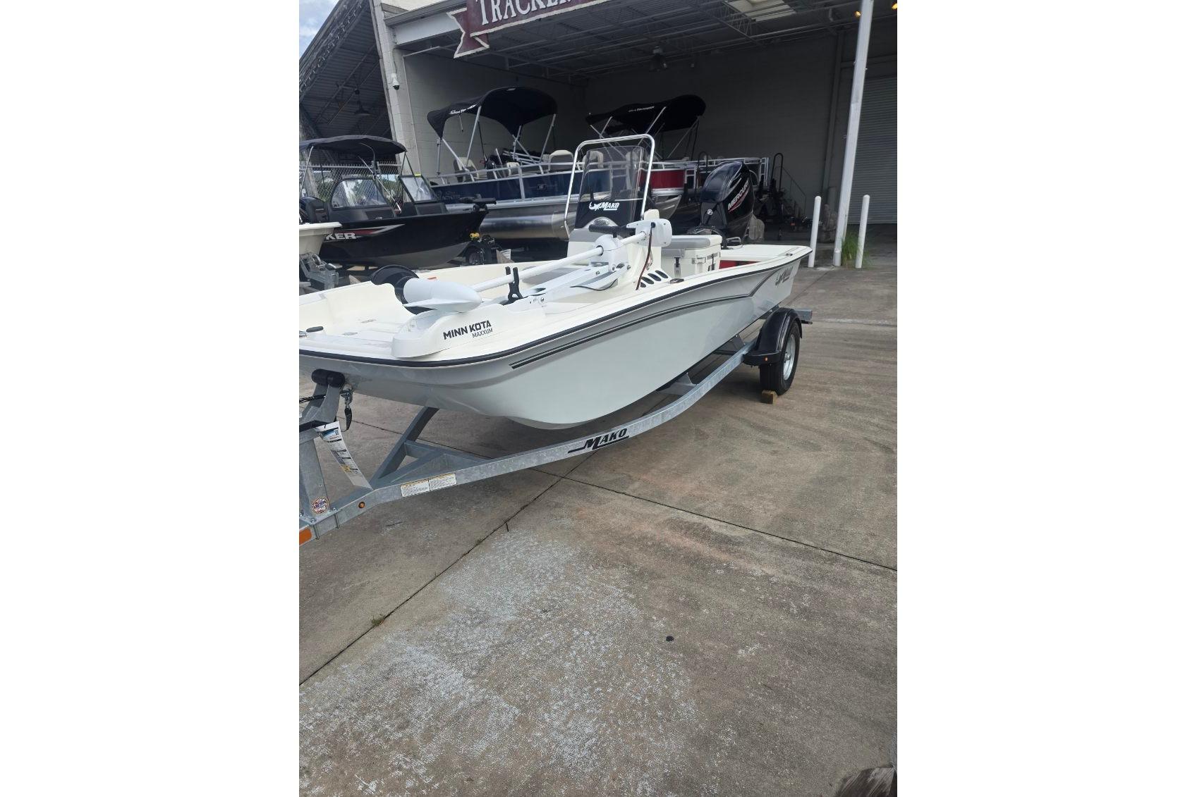 2026 Mako Pro Skiff 15 CC boat on trailer, parked outside dealership.