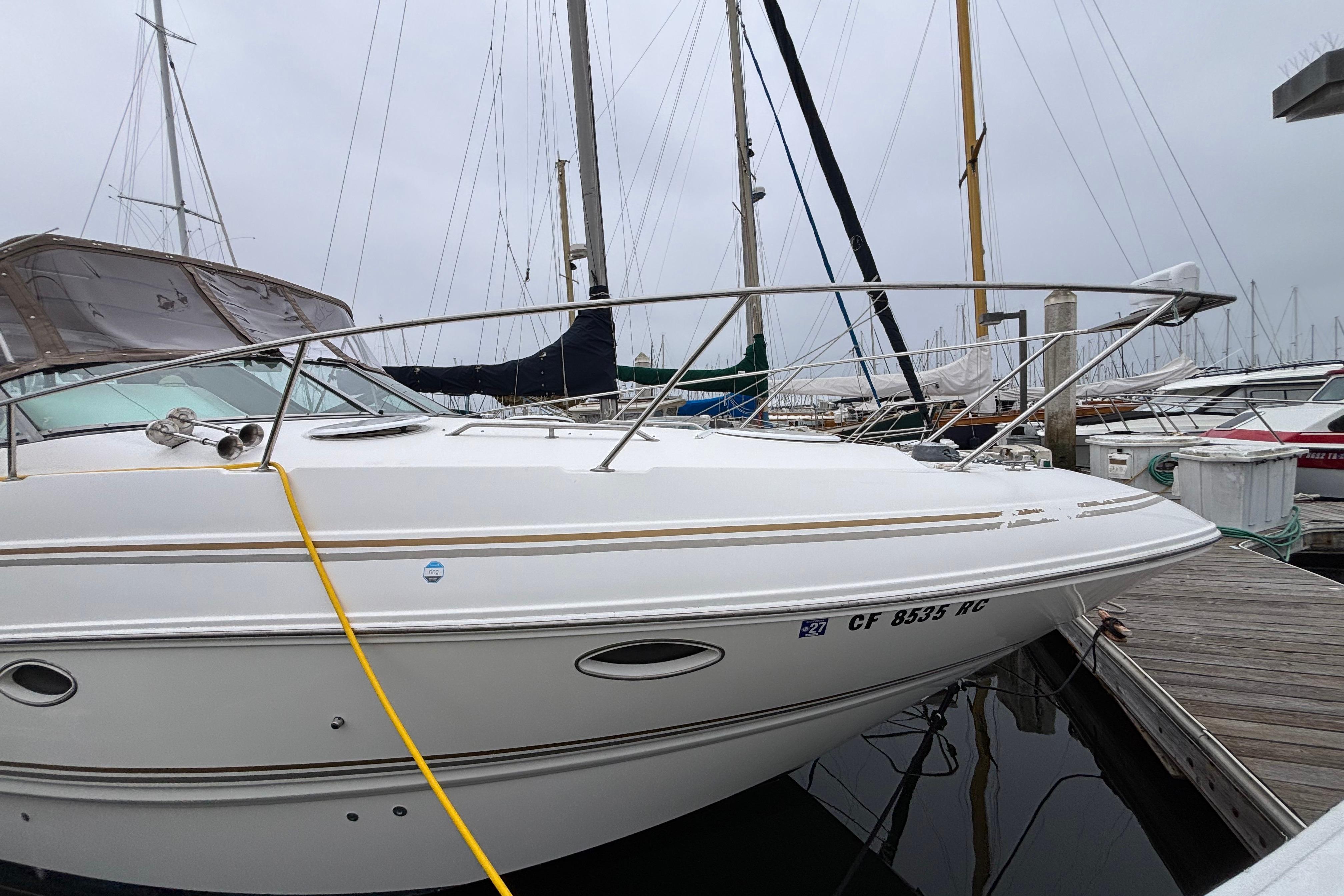 2004 Larson 310 boat docked at marina, surrounded by other sailboats.