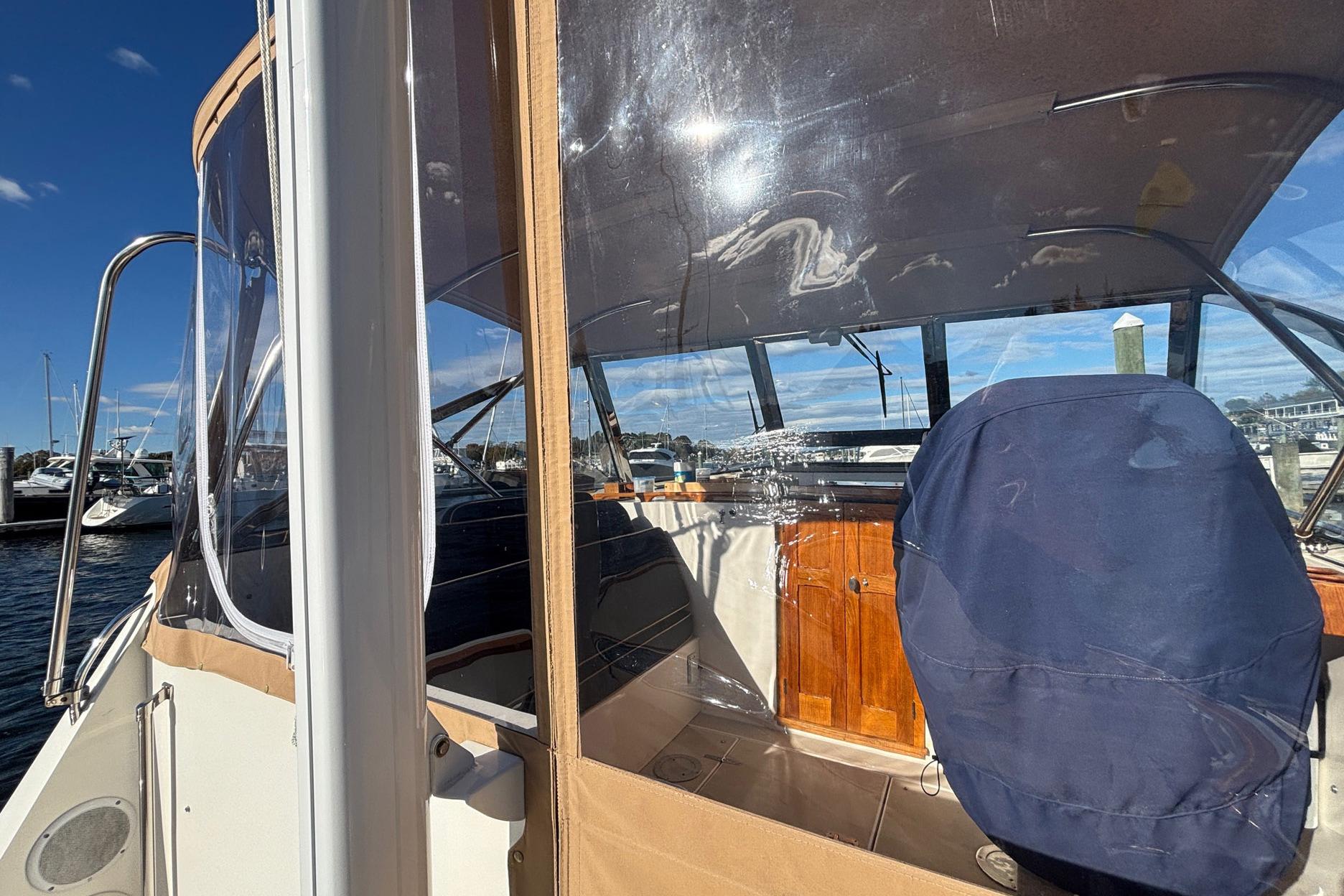 Bruckmann 30 boat from 2000 with covered seating and clear enclosure, docked at marina.