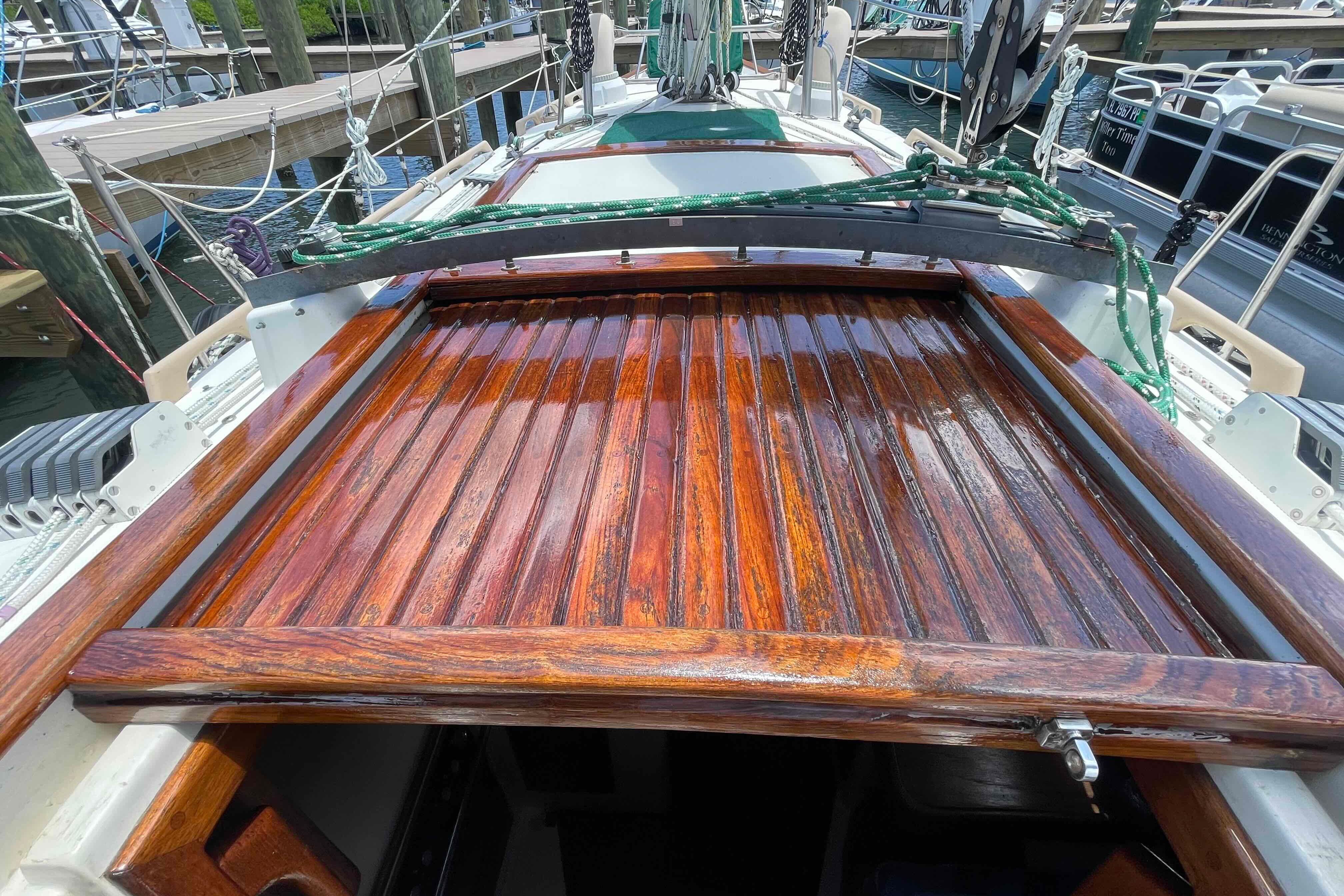 1987 Pacific Seacraft 34 sailboat with polished wooden hatch in marina setting.