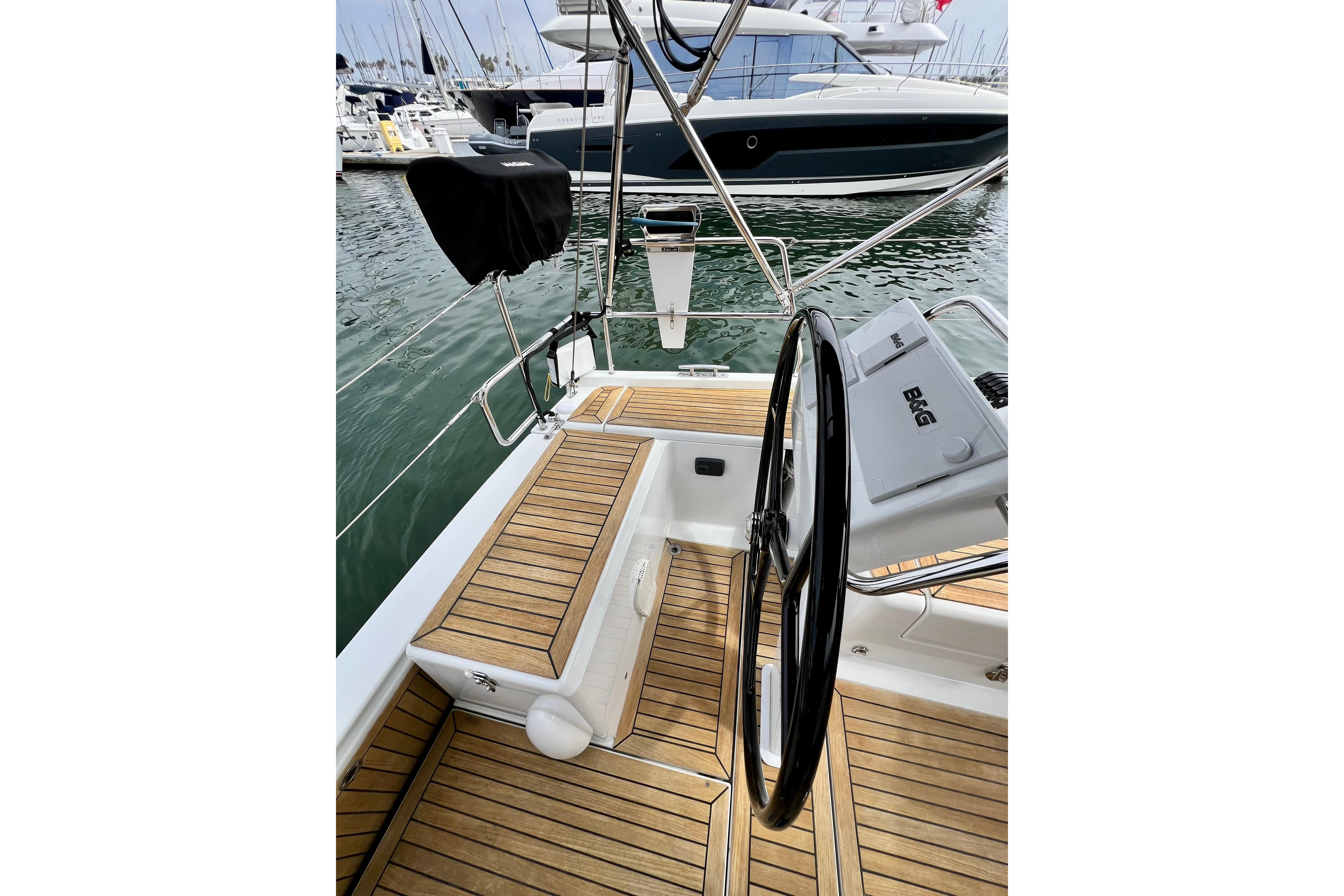 Cockpit of 2016 Hanse 455 yacht with teak flooring and steering wheel, docked at marina.