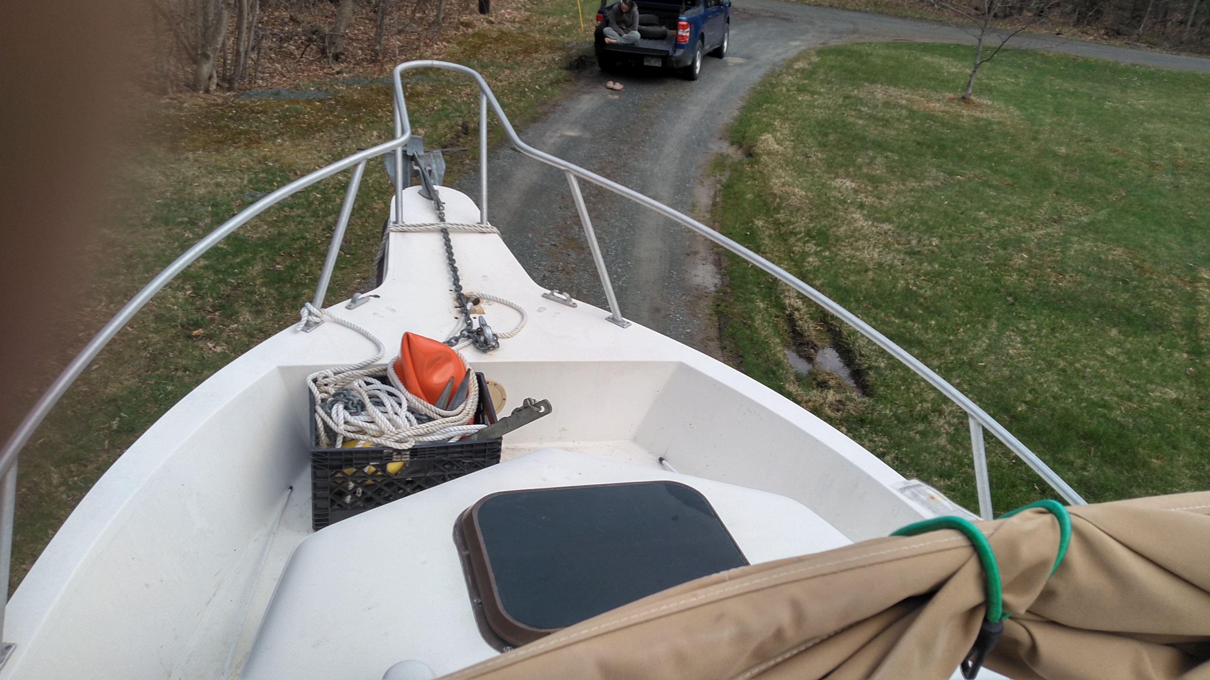 A boat on a trailer with ropes and an orange buoy on deck.