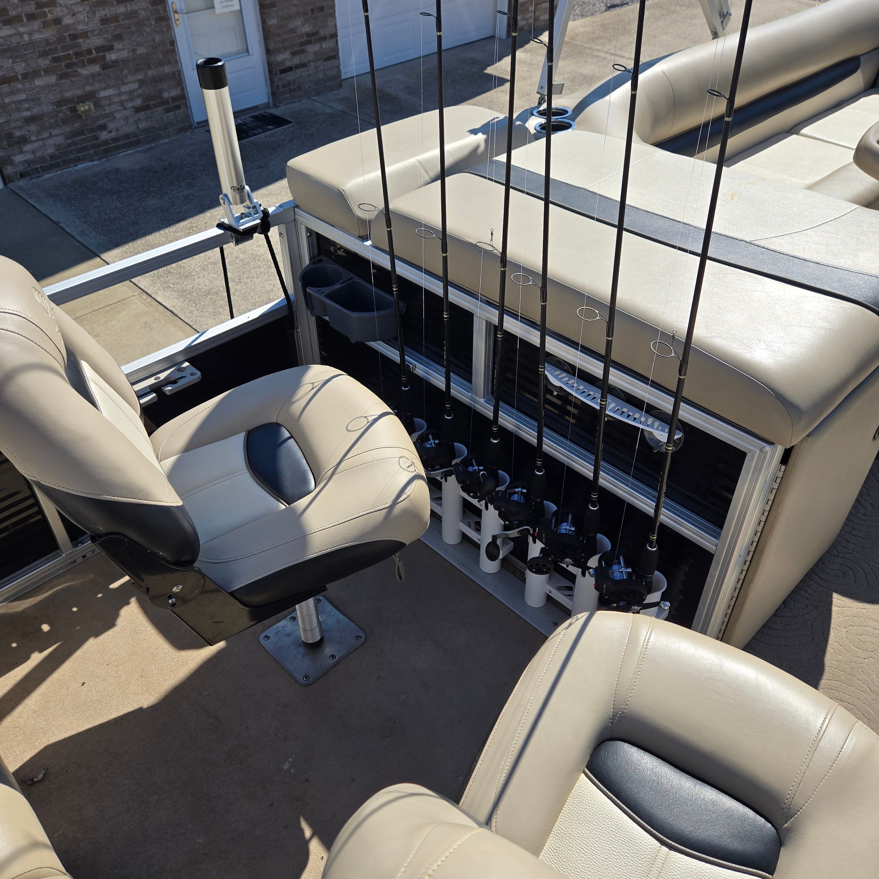 Fishing rods are secured in a holder on a boat, surrounded by beige seating.