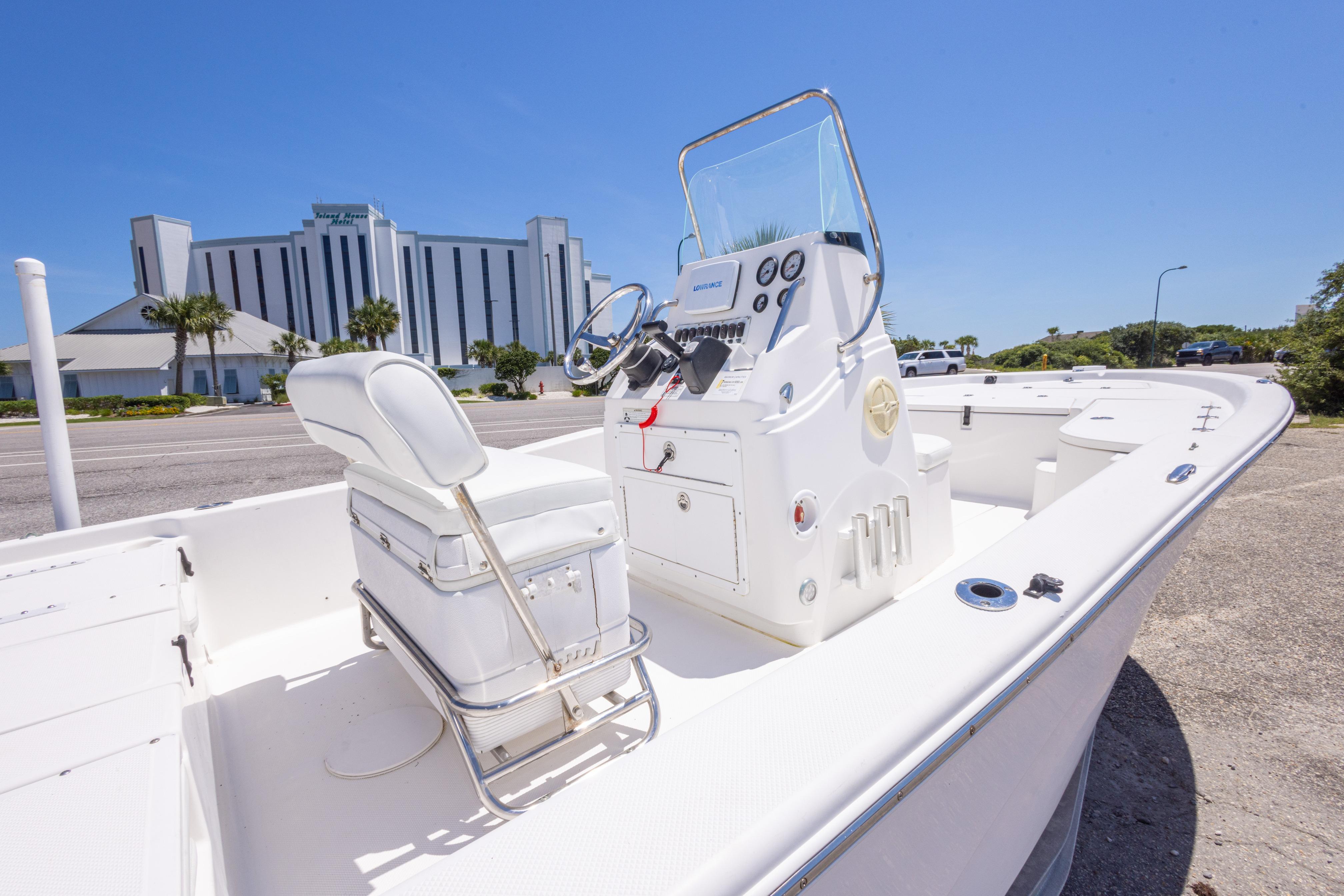 2011 Sea Fox 200XT boat with white interior, parked near a modern building under clear blue skies.