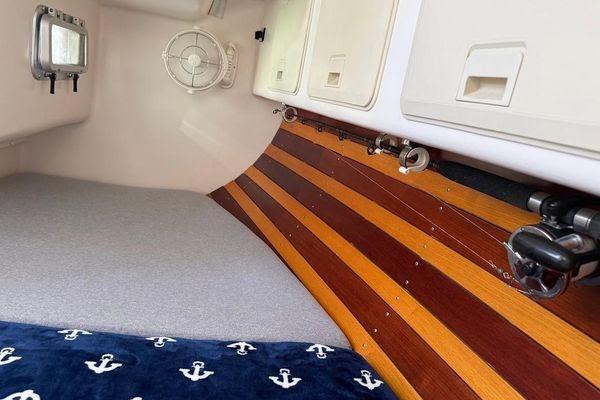 Cozy interior of 2011 Reliance 44 boat with striped wood paneling and anchor-patterned blanket.