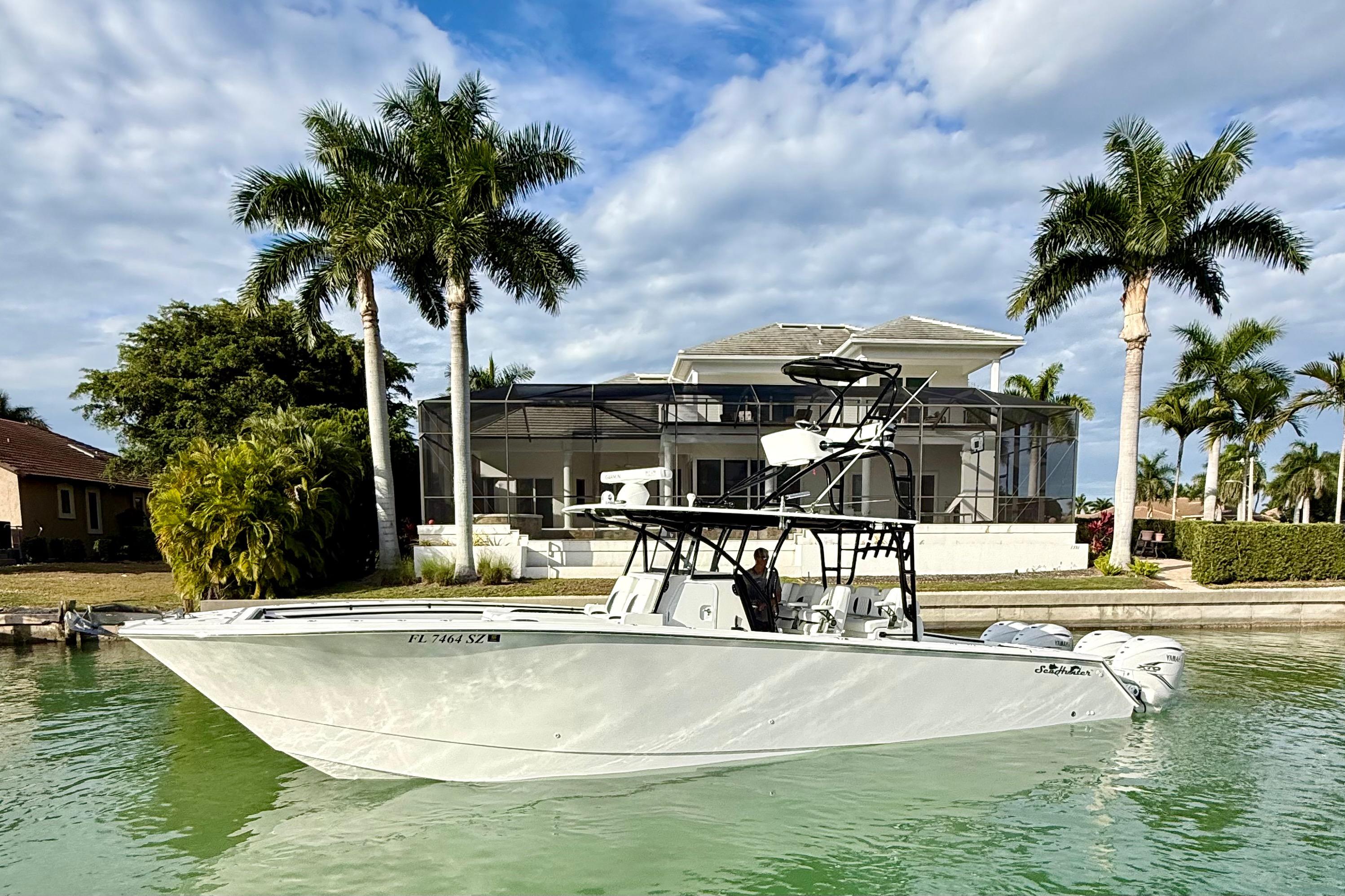 2020 SeaHunter 41 CTS boat on water, with palm trees and a house in the background.