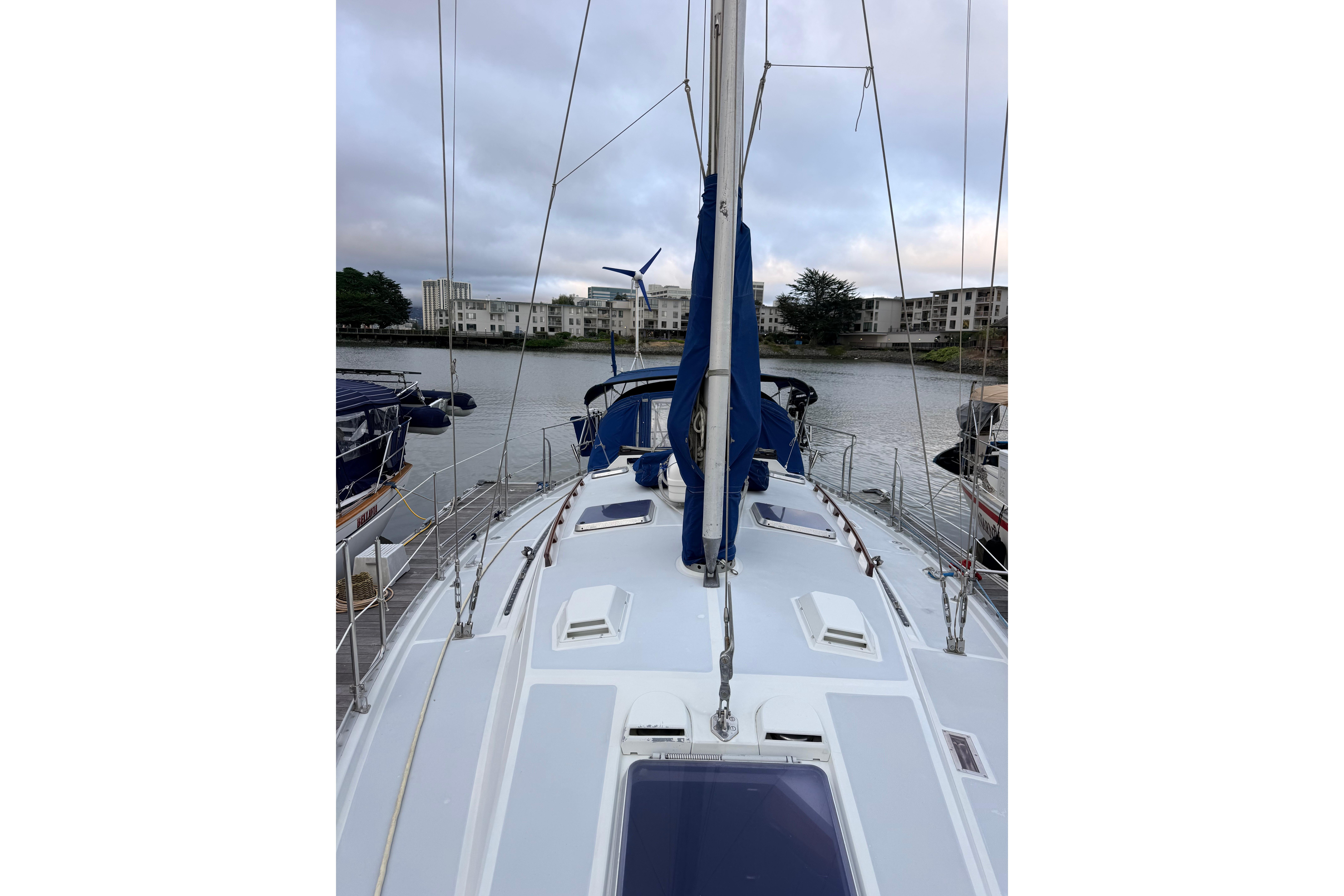 1987 Norseman 400 sailboat docked, showcasing deck and mast, with waterfront buildings in background.