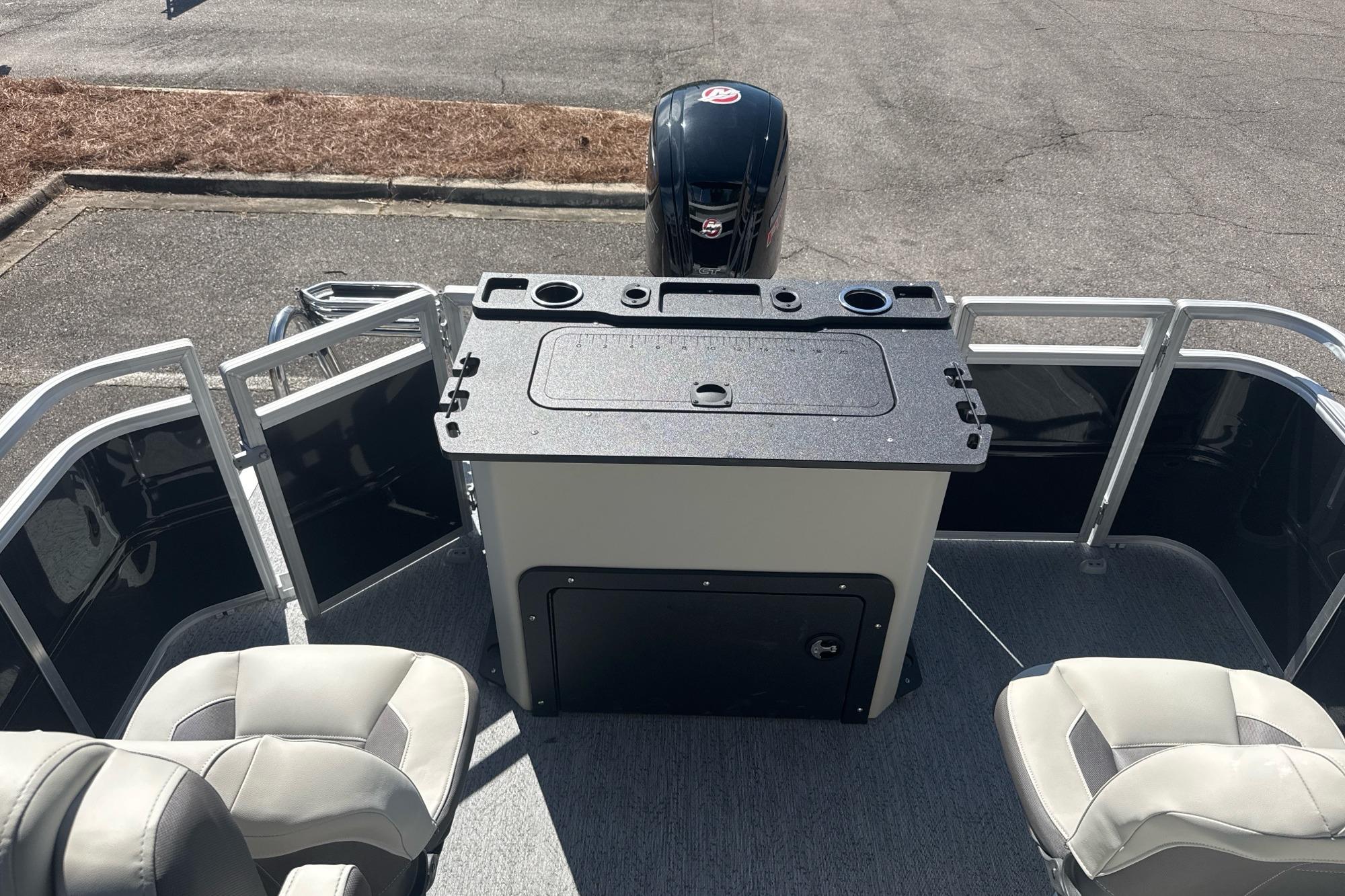 2026 Sun Tracker Fishin' Barge 20 DLX interior with seating and motor view.