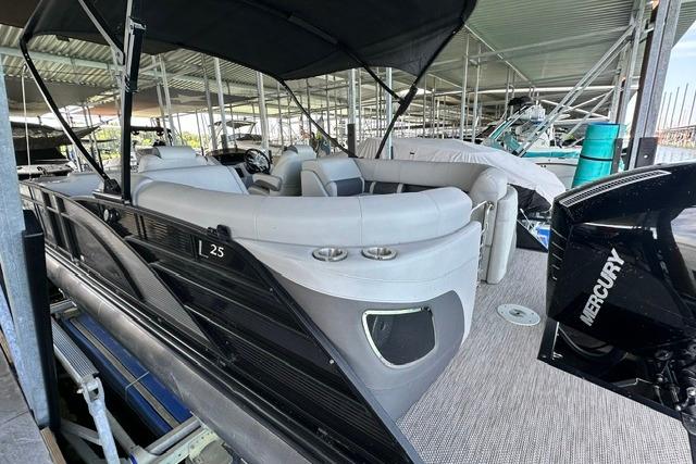 2021 Bennington L Bowrider 25 Quad Bench pontoon boat docked under cover.