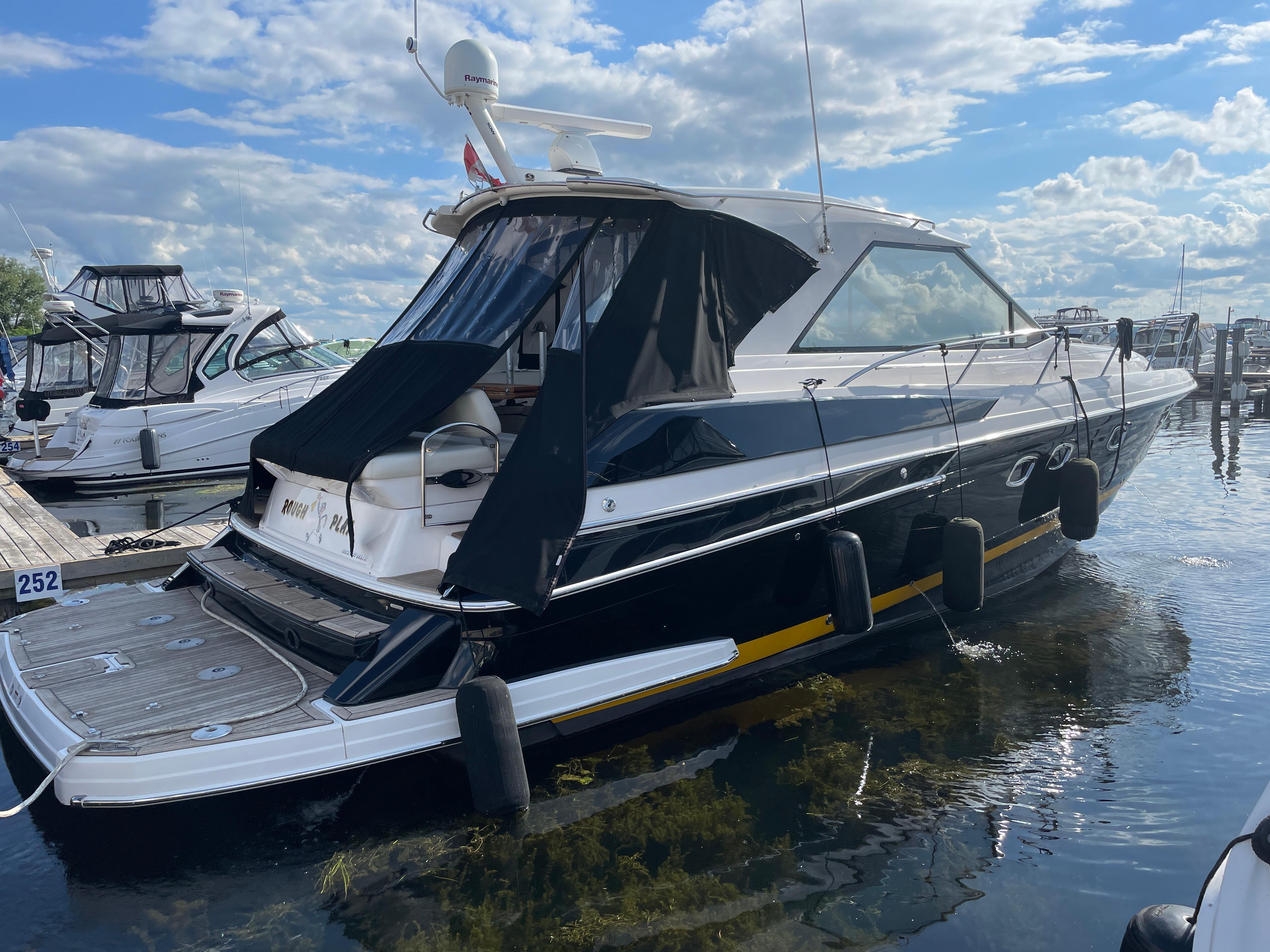 2010 Regal 44 Sport Coupe yacht docked at marina under blue sky.