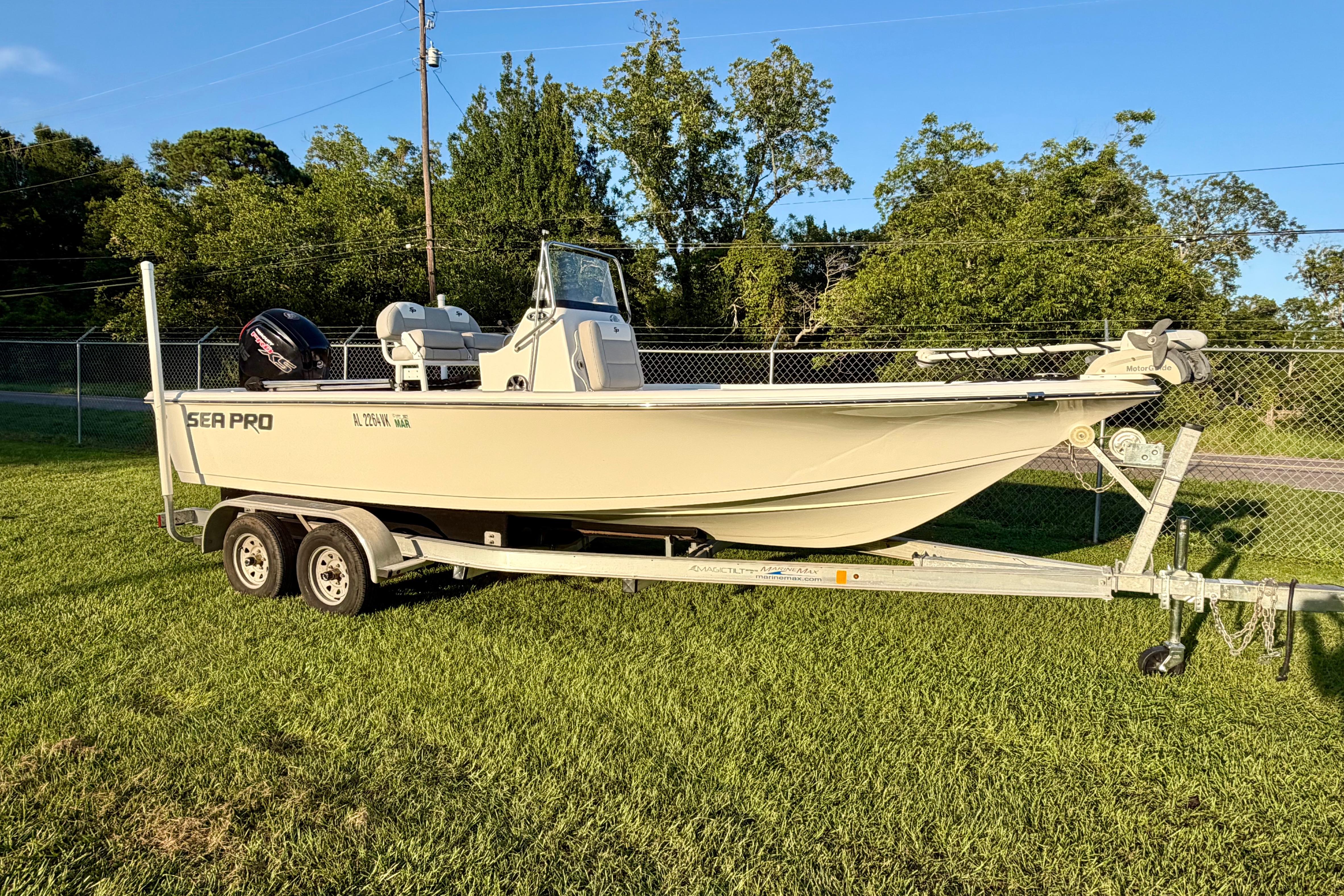 2018 Sea Pro 208 Bay boat on trailer, parked on grass with trees in background.