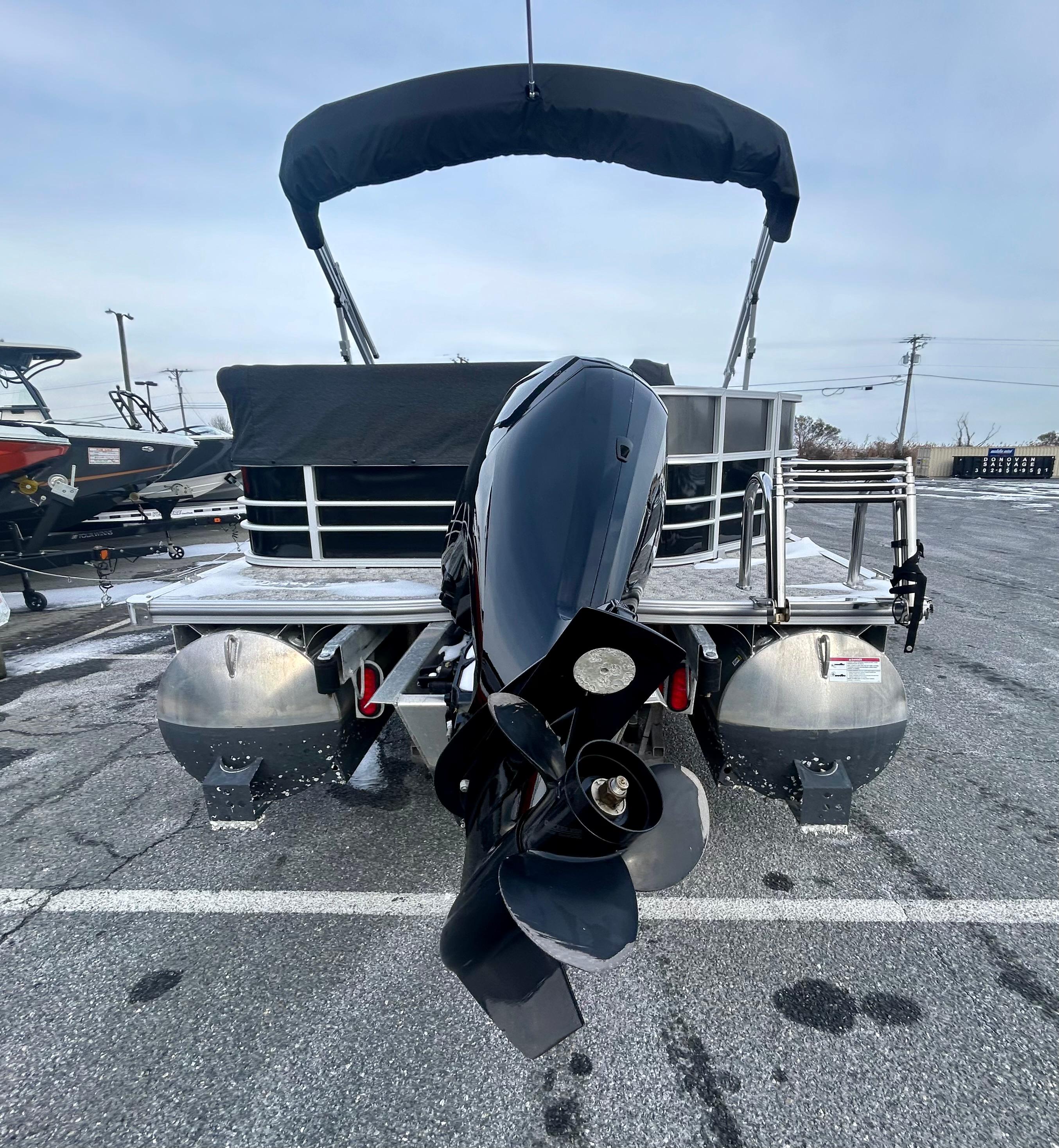 2024 Berkshire 24CL LE 2.75 pontoon boat with outboard motor, parked on asphalt.