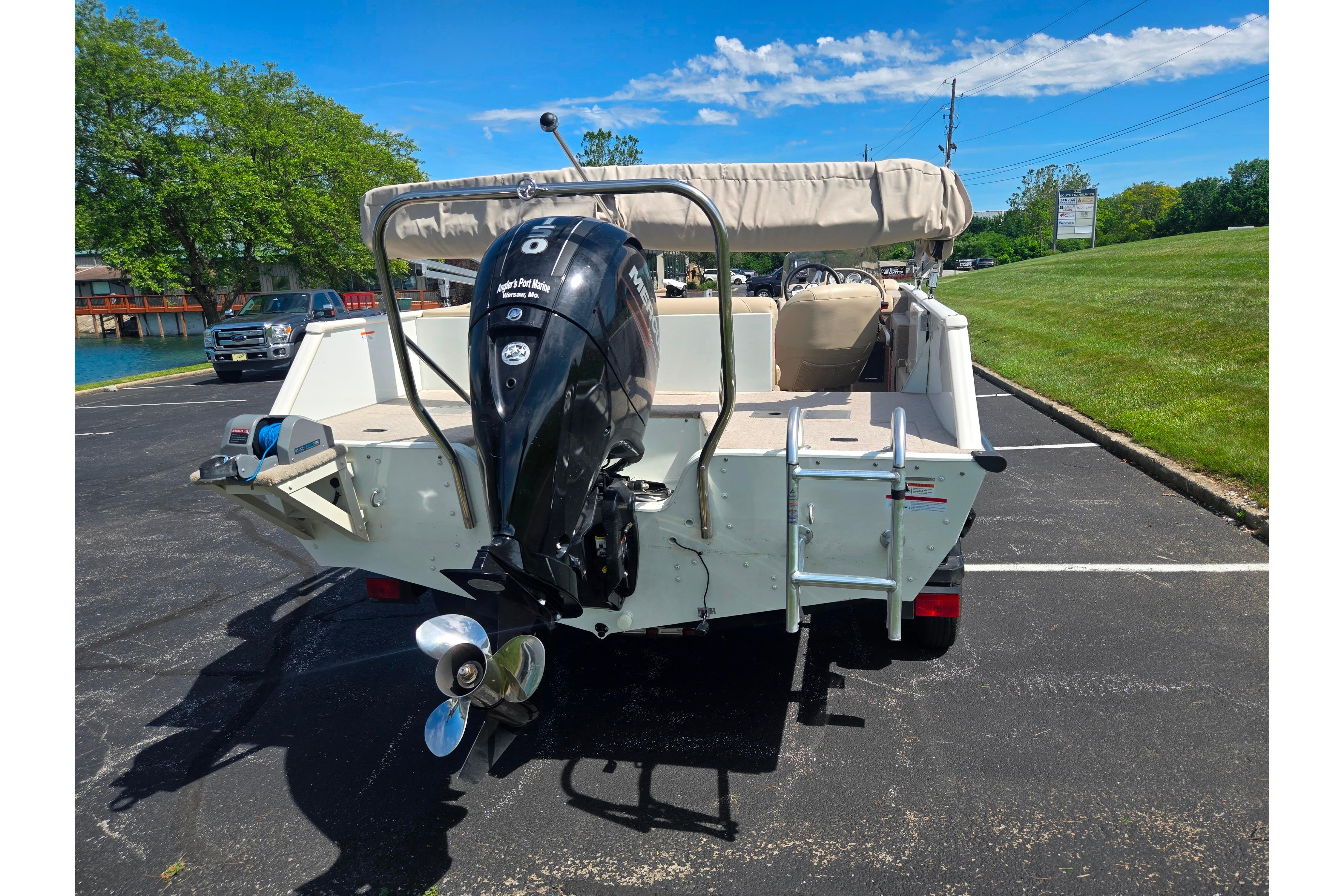 2015 Lowe Sport Deck 224 boat with outboard motor, parked on asphalt near grassy area.