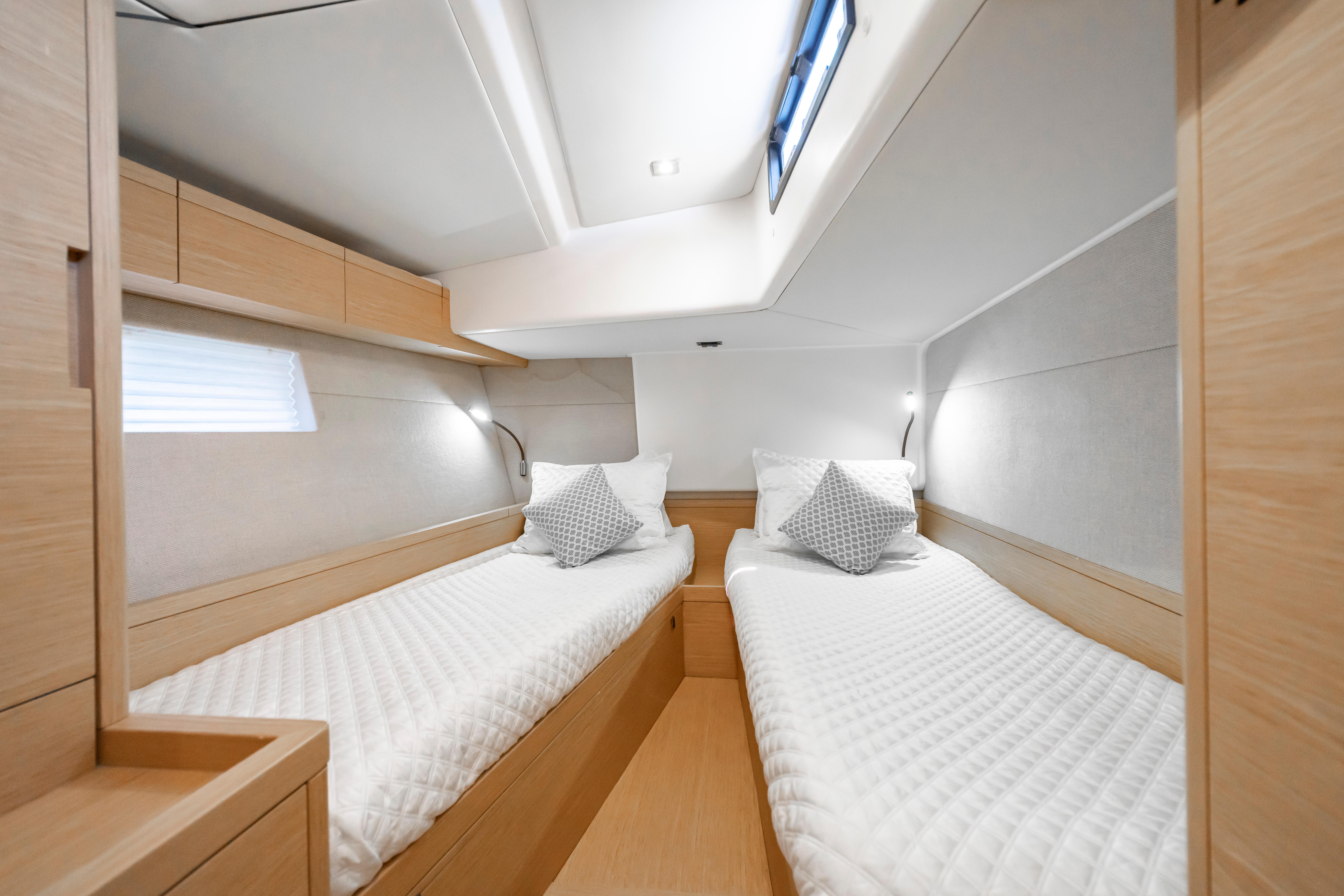 Luxurious twin cabin interior of 2016 Grand Soleil 58 yacht, featuring modern design and cozy bedding.