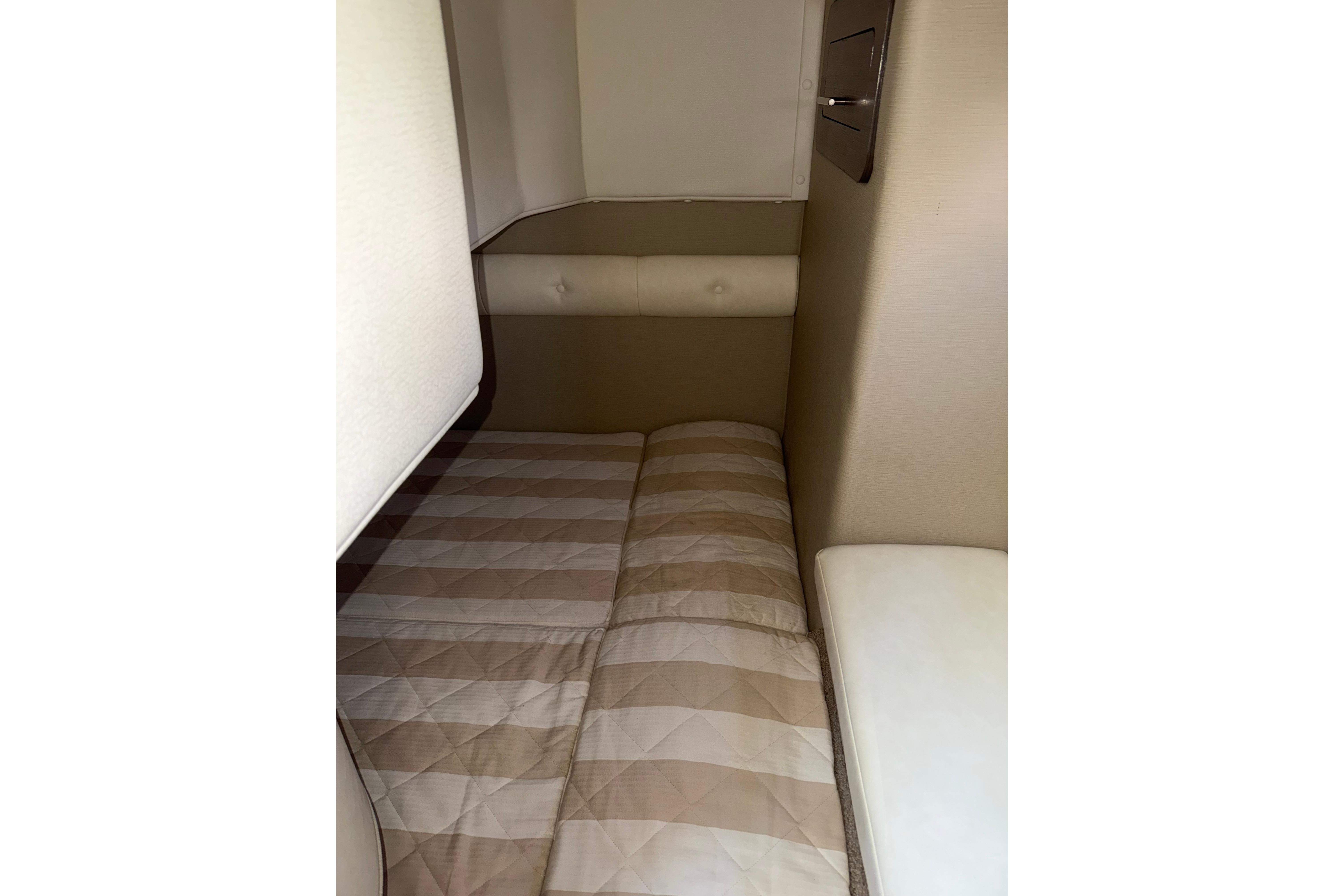 Interior cabin of 2019 Rinker EX 320 boat with beige quilted bedding.
