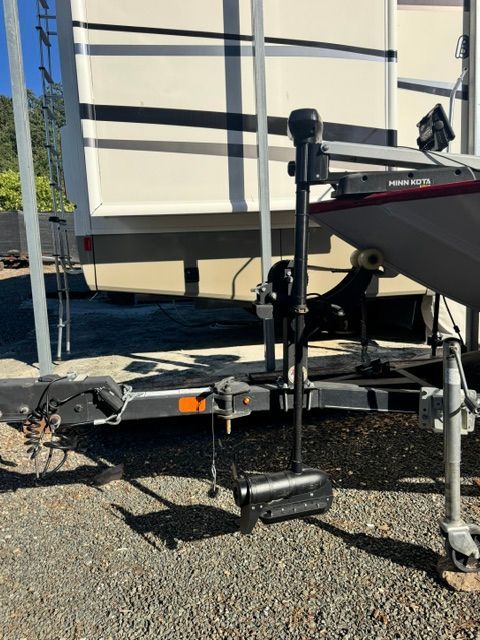 A boat trailer with a Minn Kota motor, parked next to an RV.