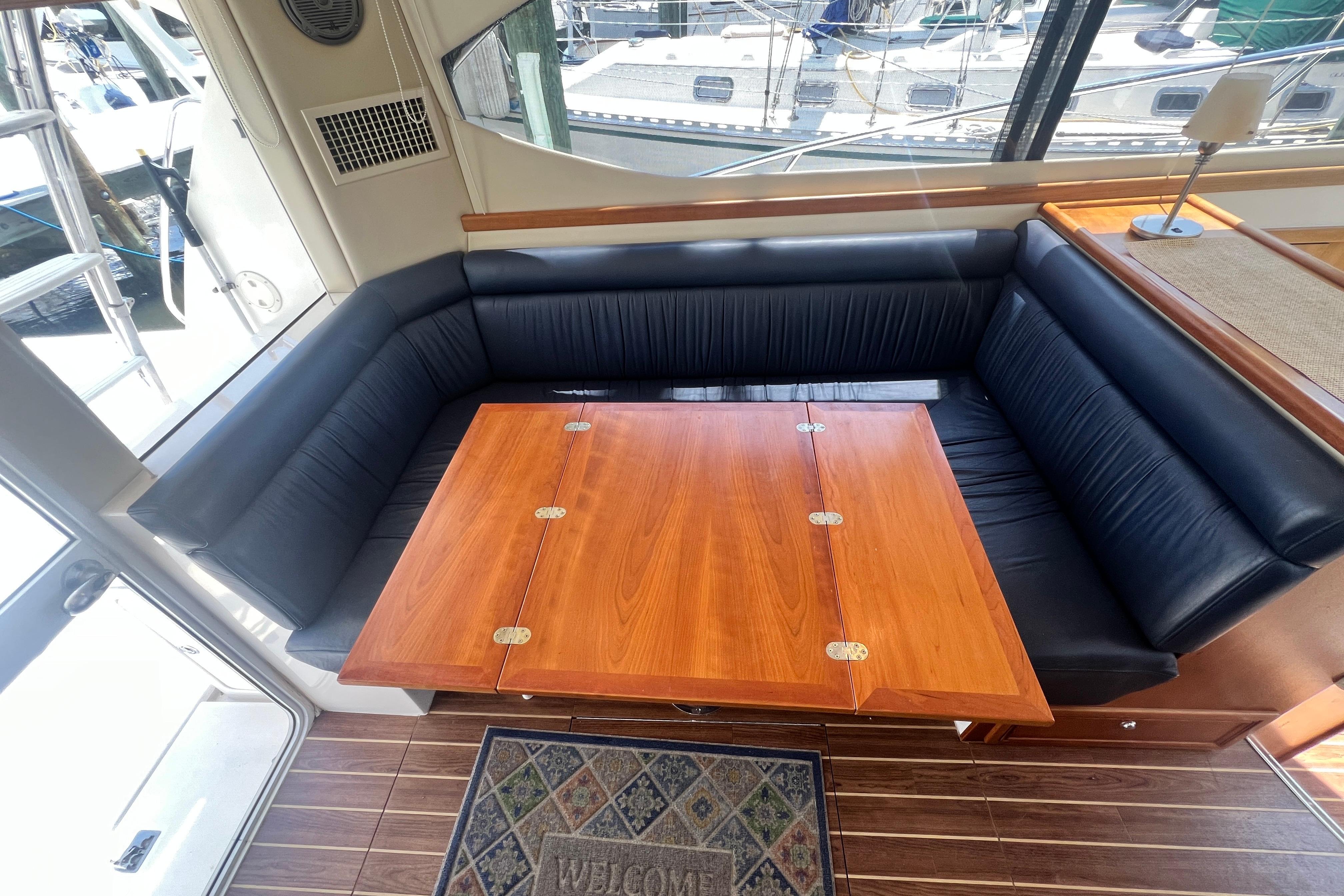 Luxurious 2007 Riviera 33 Flybridge interior with elegant wood table and black seating.