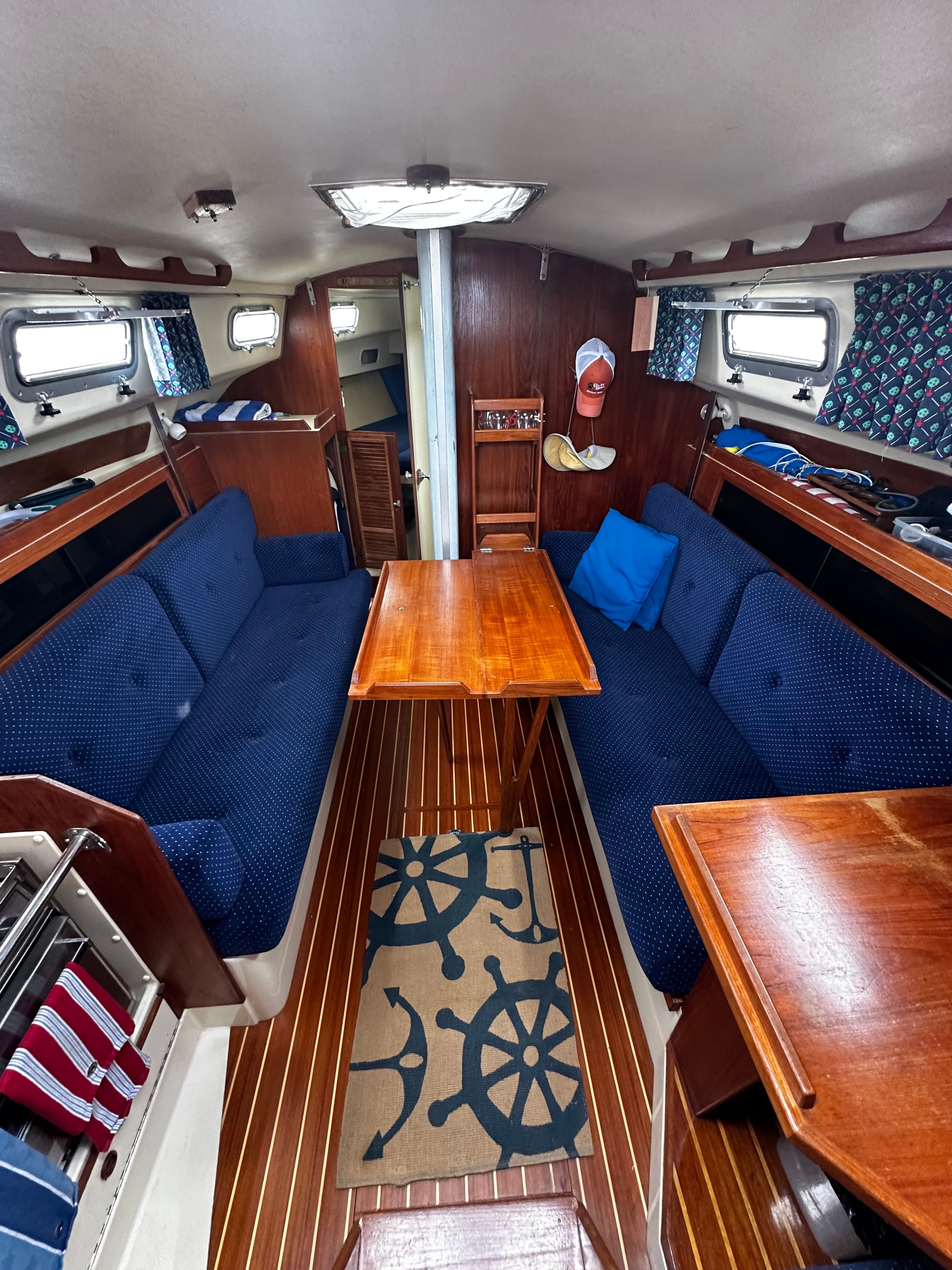 Interior of a 1984 Pearson 303 sailboat with wooden furnishings and blue upholstery.