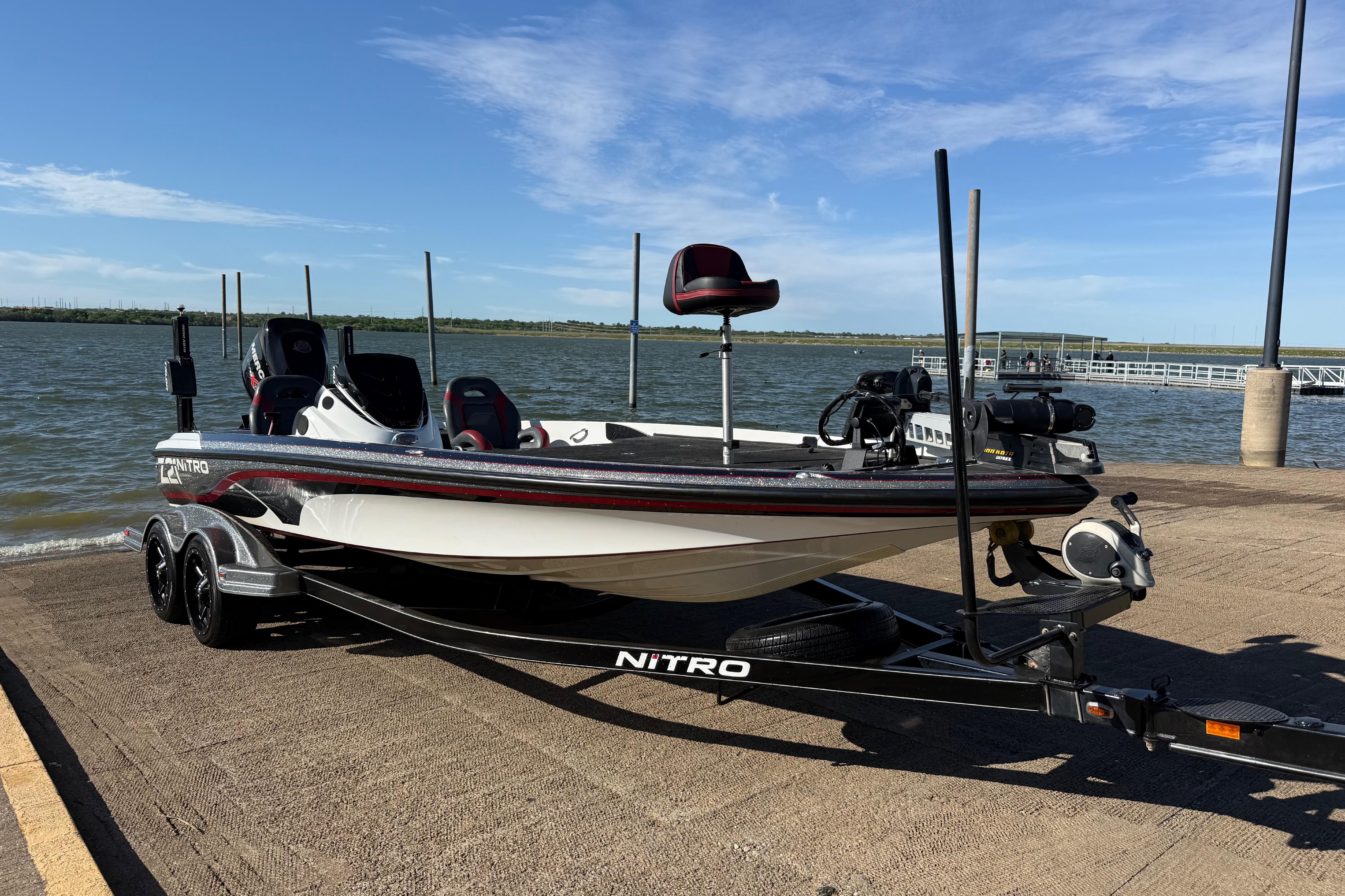 2016 Nitro Z21 boat on trailer by a lake under clear blue sky.