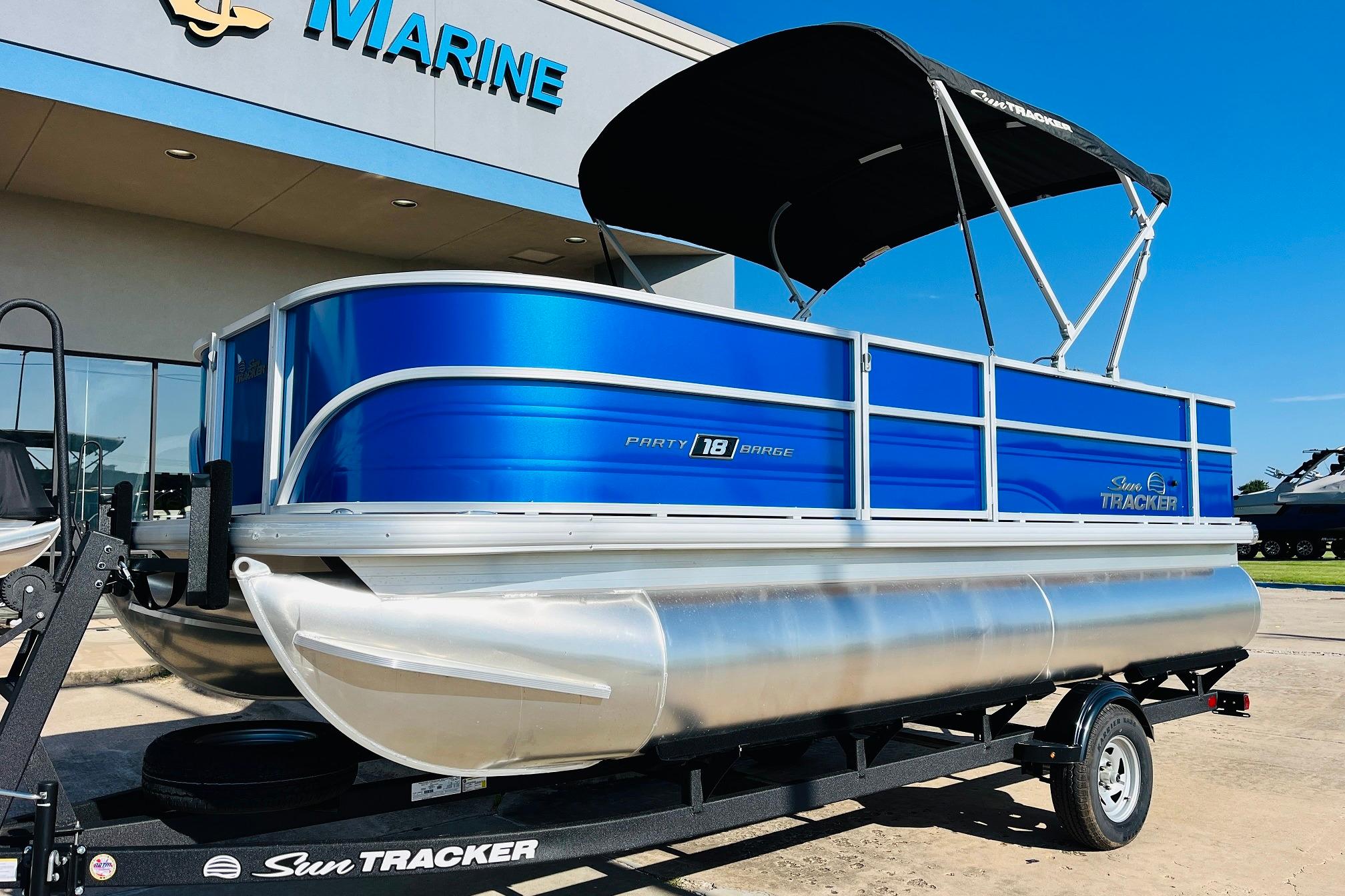 2026 Sun Tracker Party Barge 18 DLX pontoon boat with blue exterior, parked on trailer.