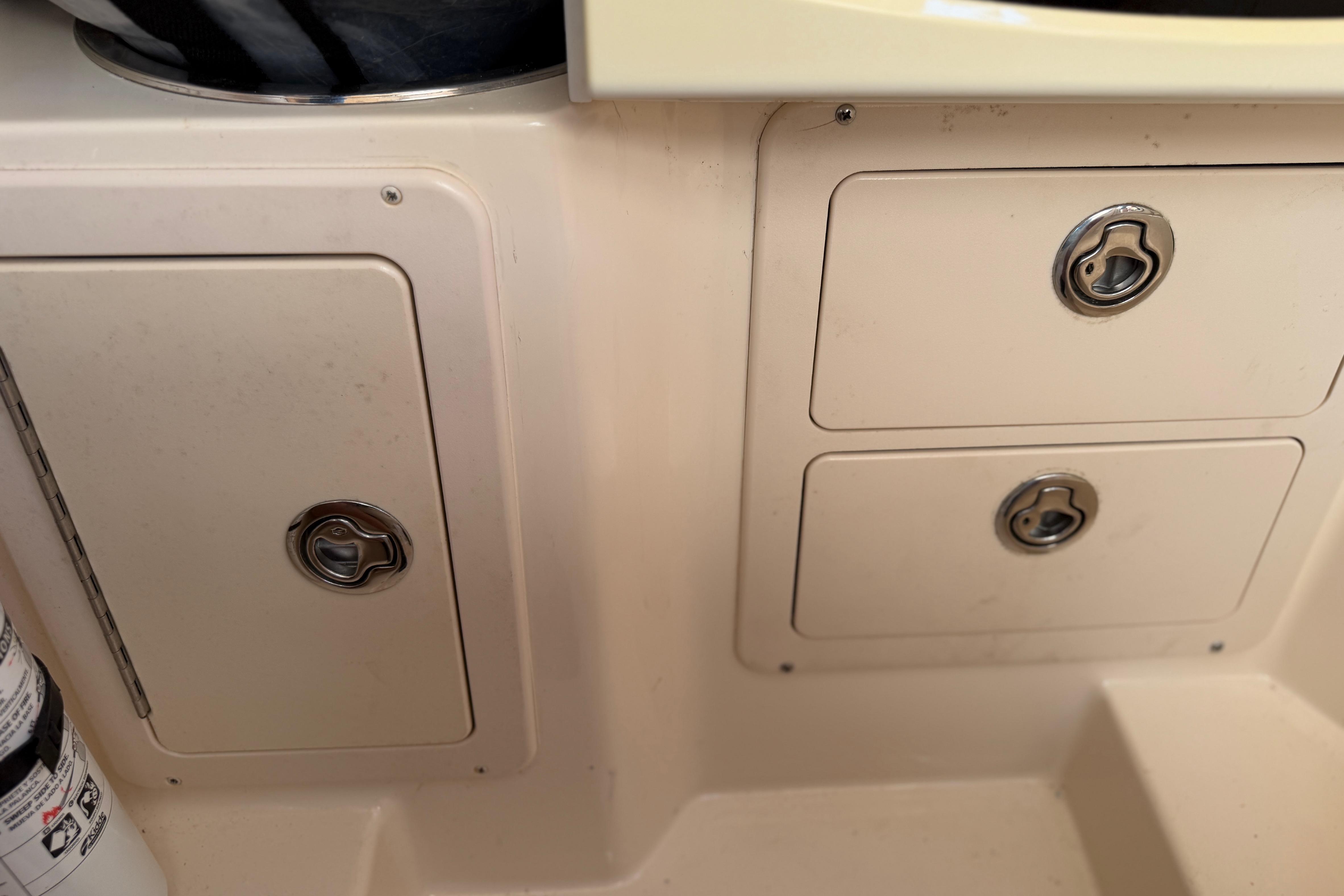 2004 Grady White 273 boat storage compartments with secure latches and fire extinguisher.