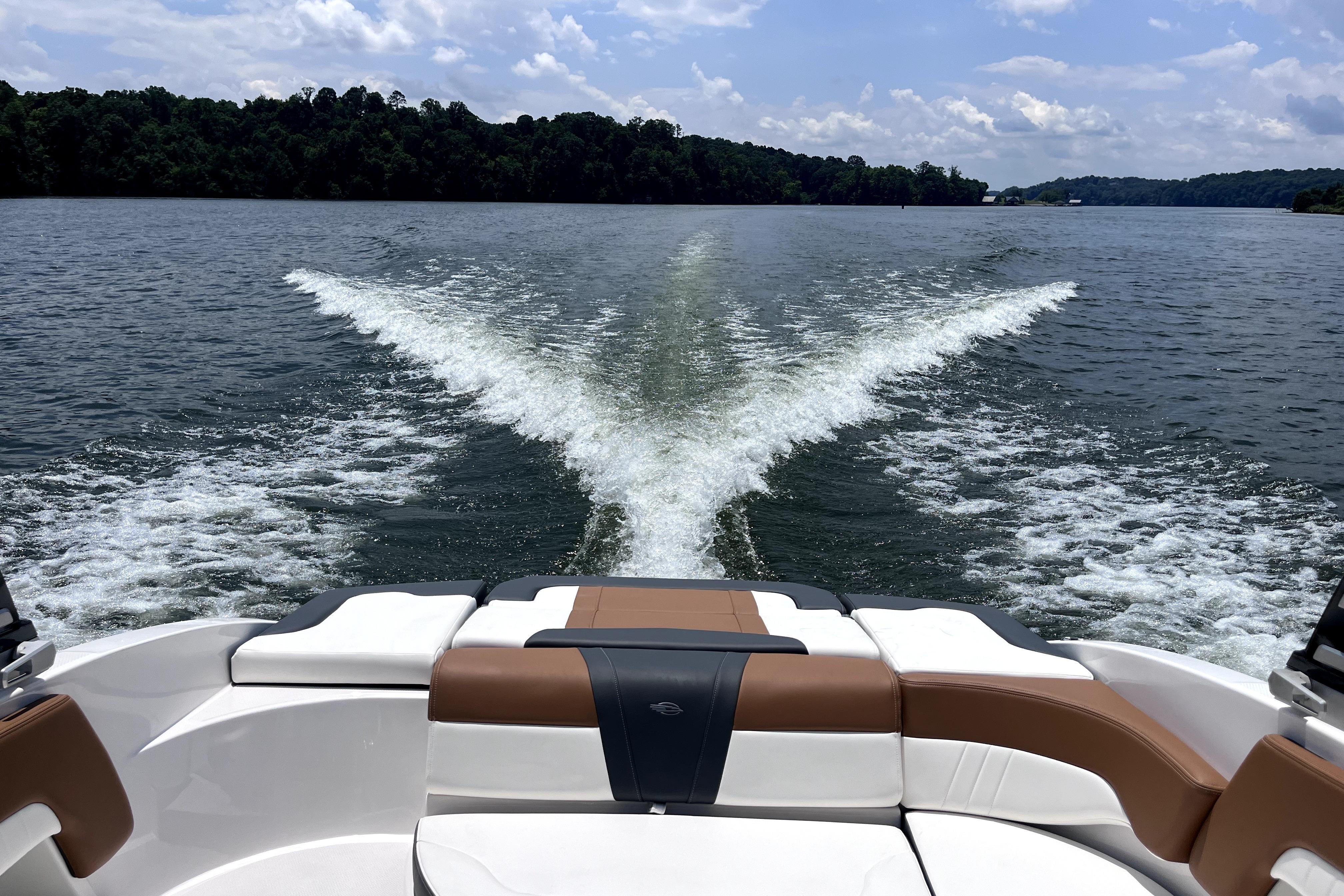 2025 Chaparral 230 SSi boat cruising on a scenic lake, leaving a wake trail.