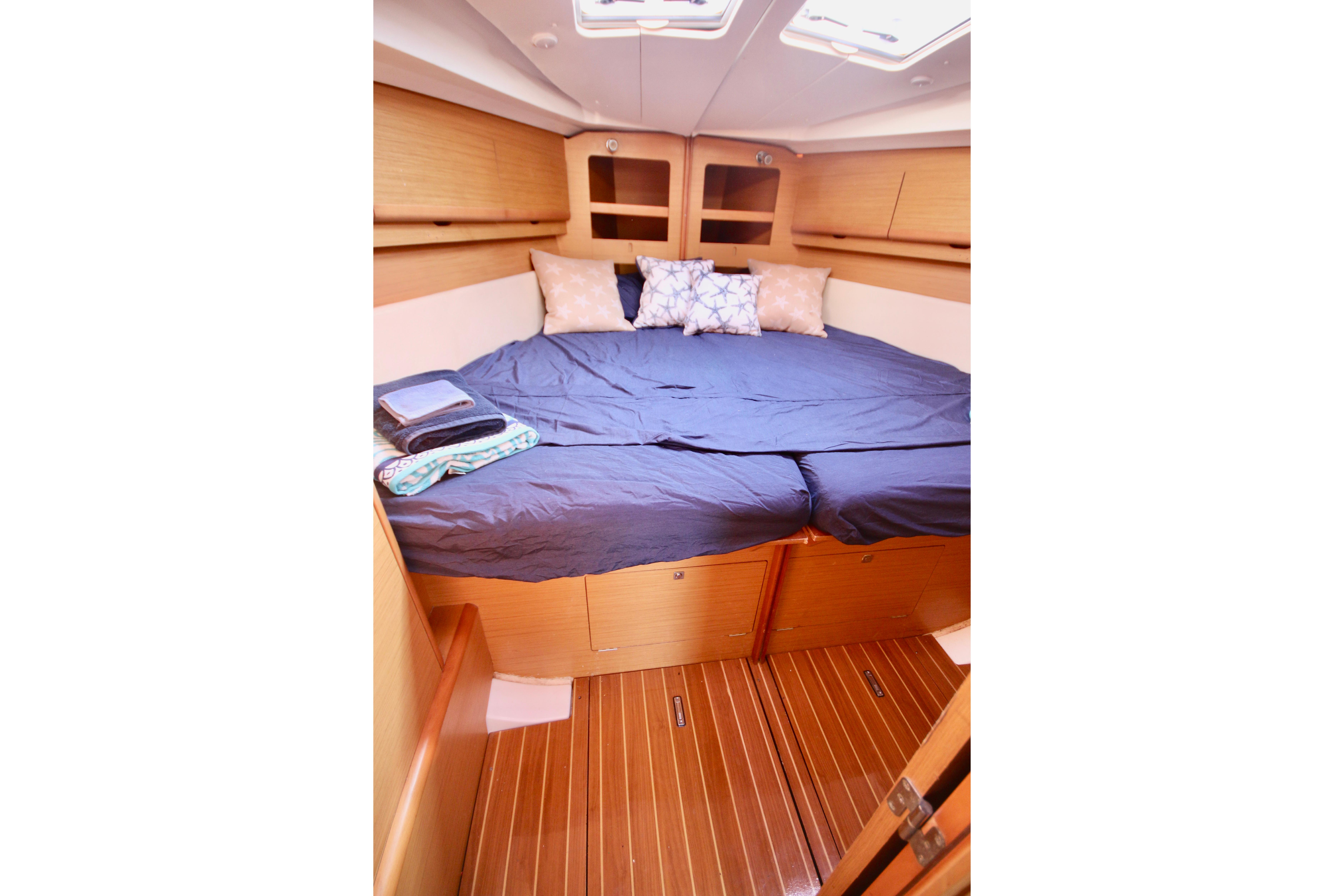 Cozy cabin interior of 2009 Jeanneau Sun Odyssey 44i with plush bedding and wooden flooring.