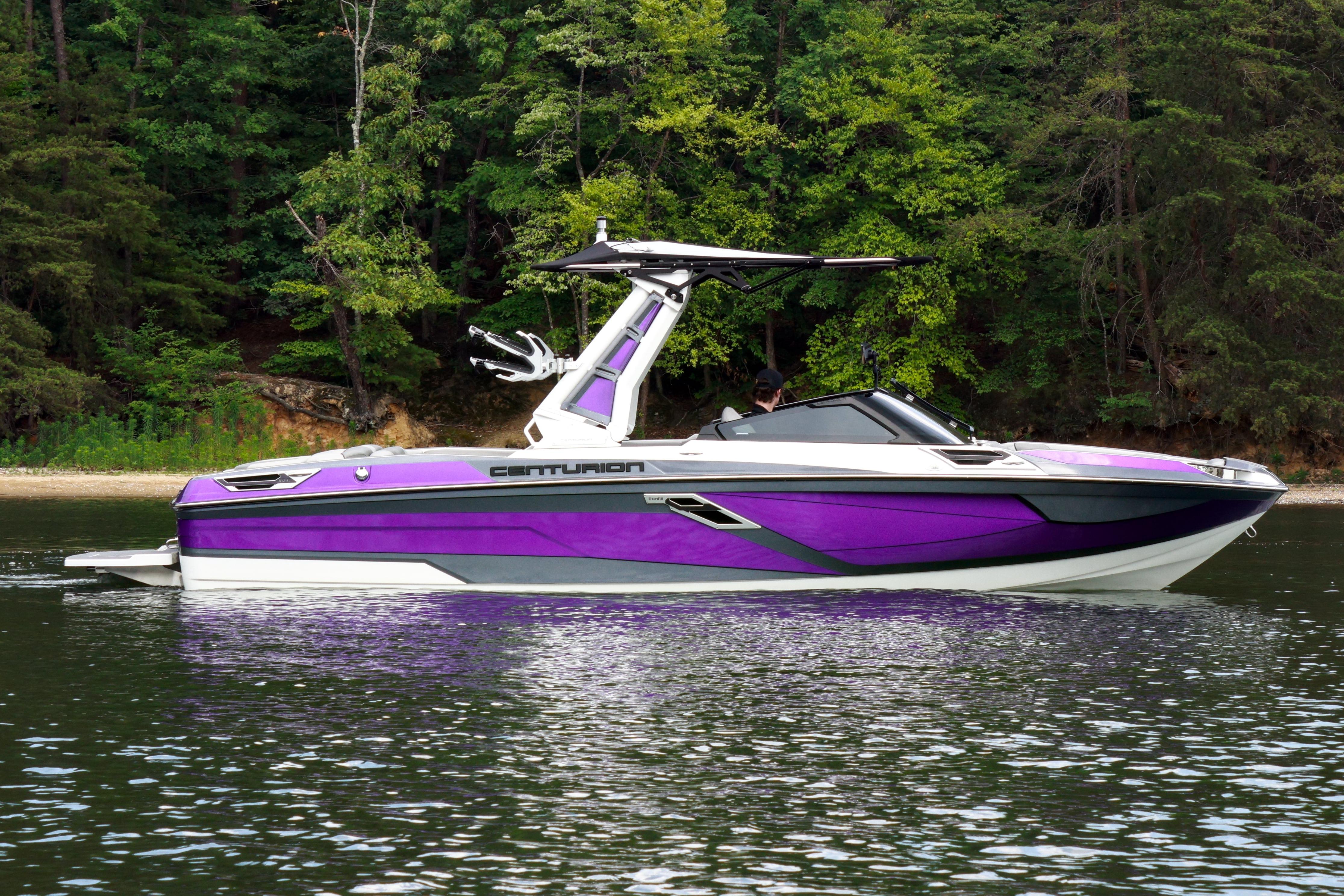 2022 Centurion Ri245 boat in vibrant purple on a calm lake, surrounded by lush trees.
