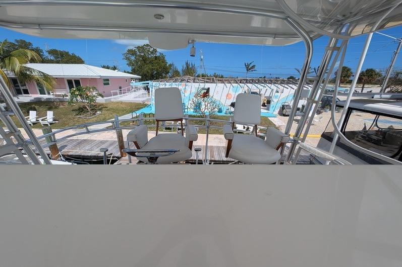 2005 Egg Harbor 43 SportYacht helm with white chairs, docked near tropical setting.