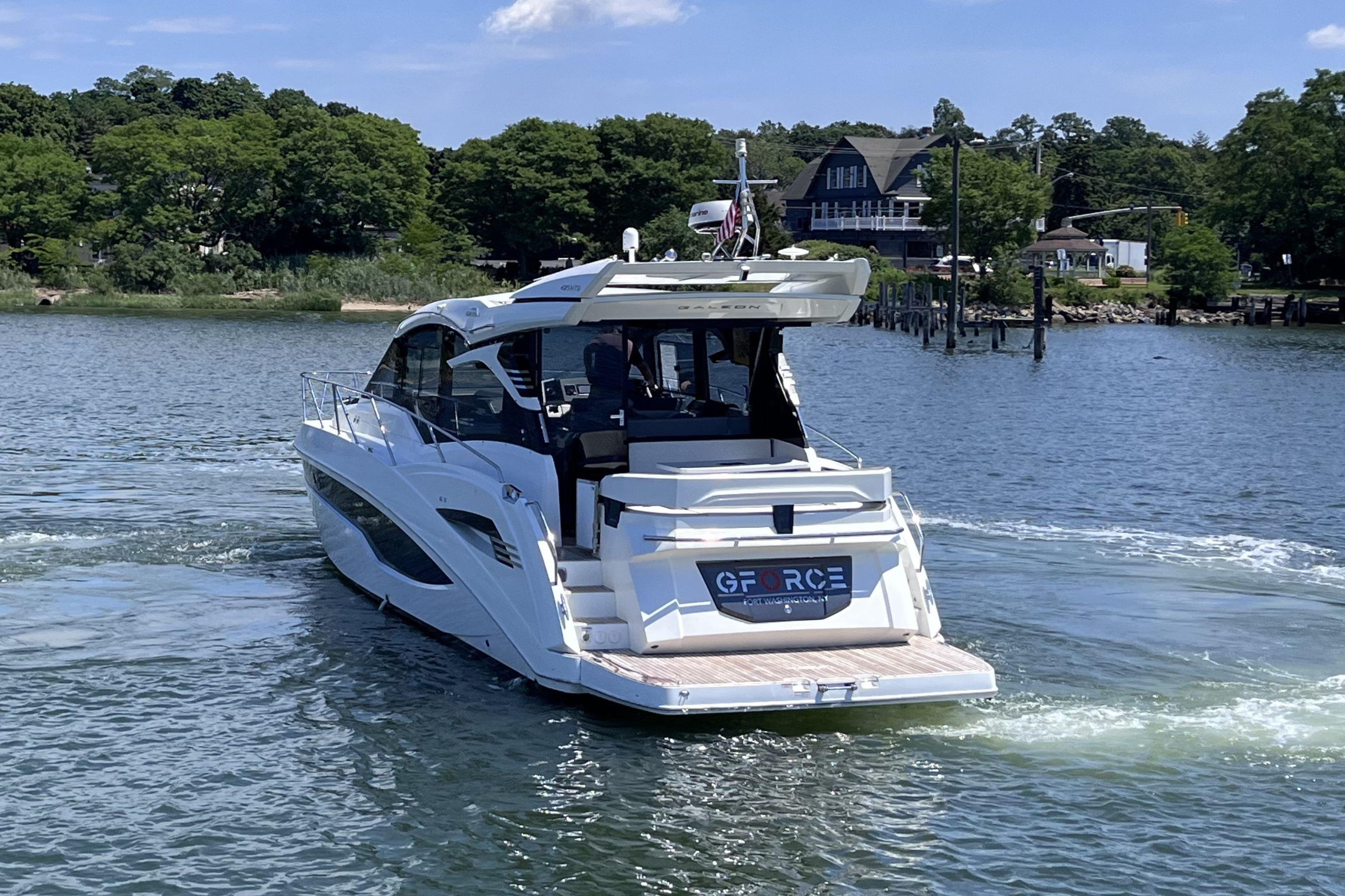 2024 Galeon 425 HTS yacht cruising on a scenic lake with lush greenery.