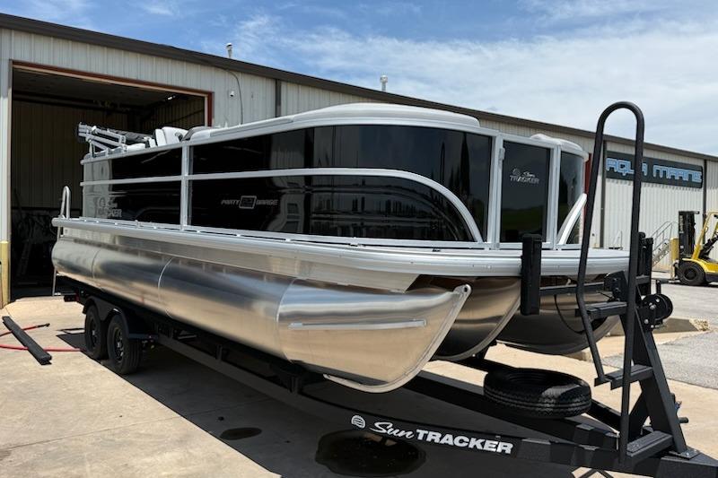 2026 Sun Tracker Party Barge 22 XP3 pontoon boat on trailer outside warehouse.