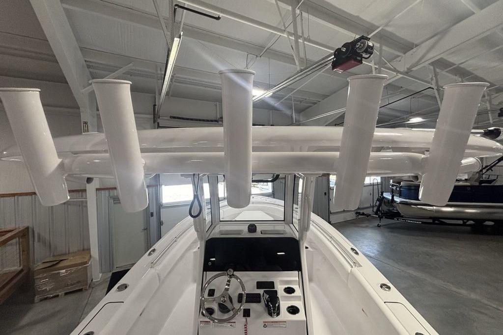 2026 Sportsman Open 252 Center Console boat interior with rod holders in a showroom.