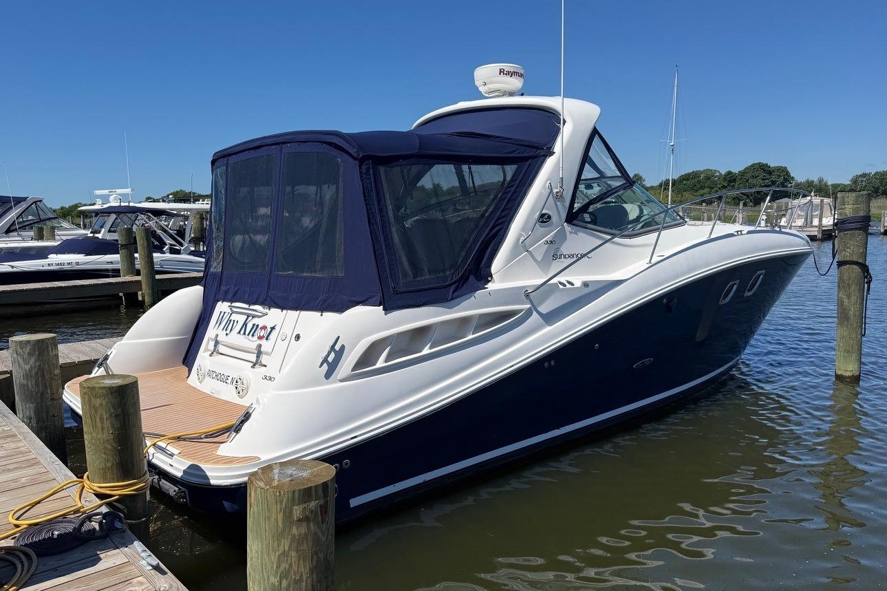 2008 Sea Ray Sundancer 330 docked at marina, featuring sleek design and blue canopy.