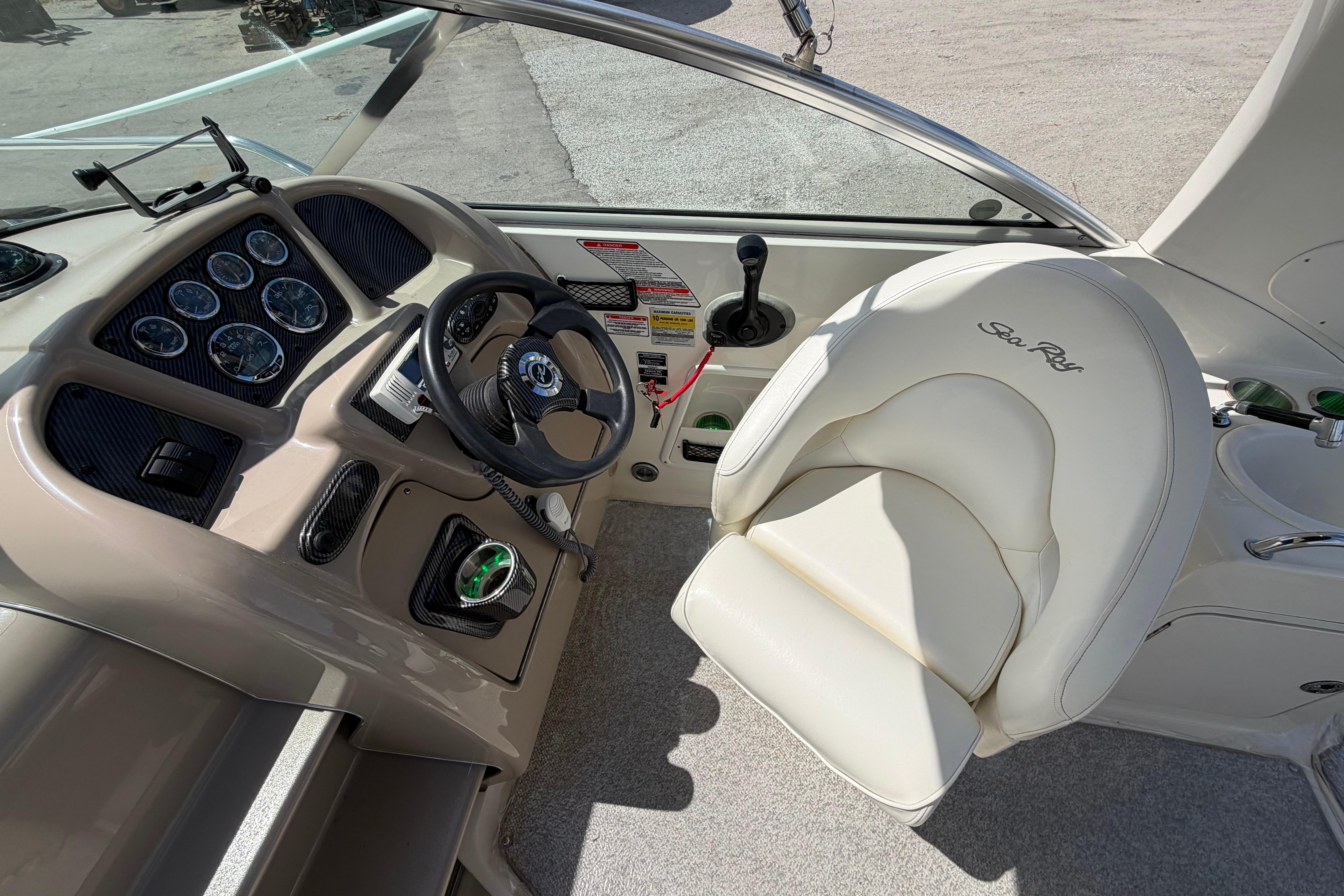 2004 Sea Ray Sundancer 260 helm with steering wheel and gauges, featuring a white captain's chair.