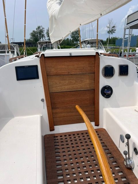 The cockpit of a 1969 Morgan 30 with a wooden door and tiller. Other boats in the background.
