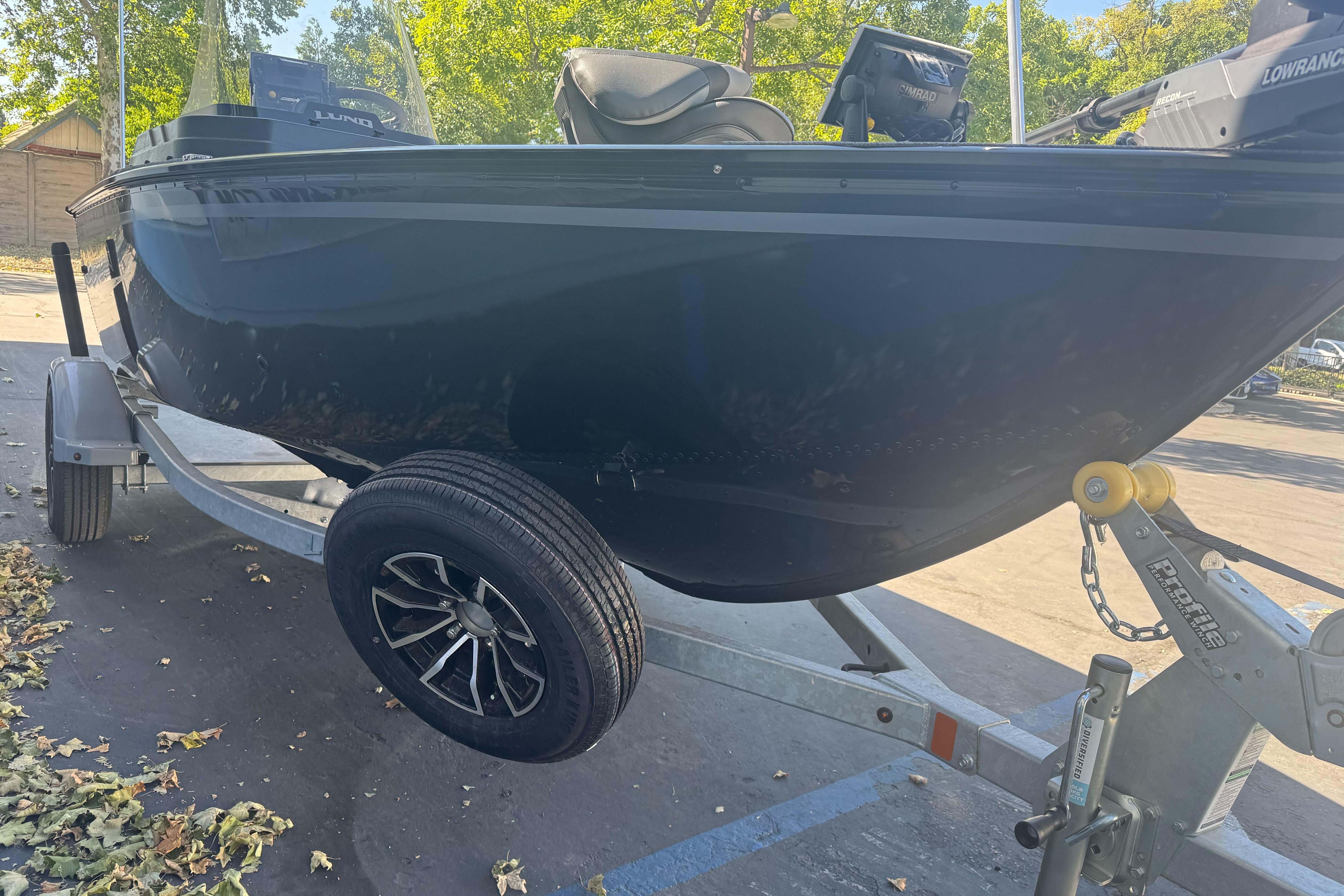 2026 Lund 1650 Rebel XL SS boat on trailer, parked outdoors with trees in background.