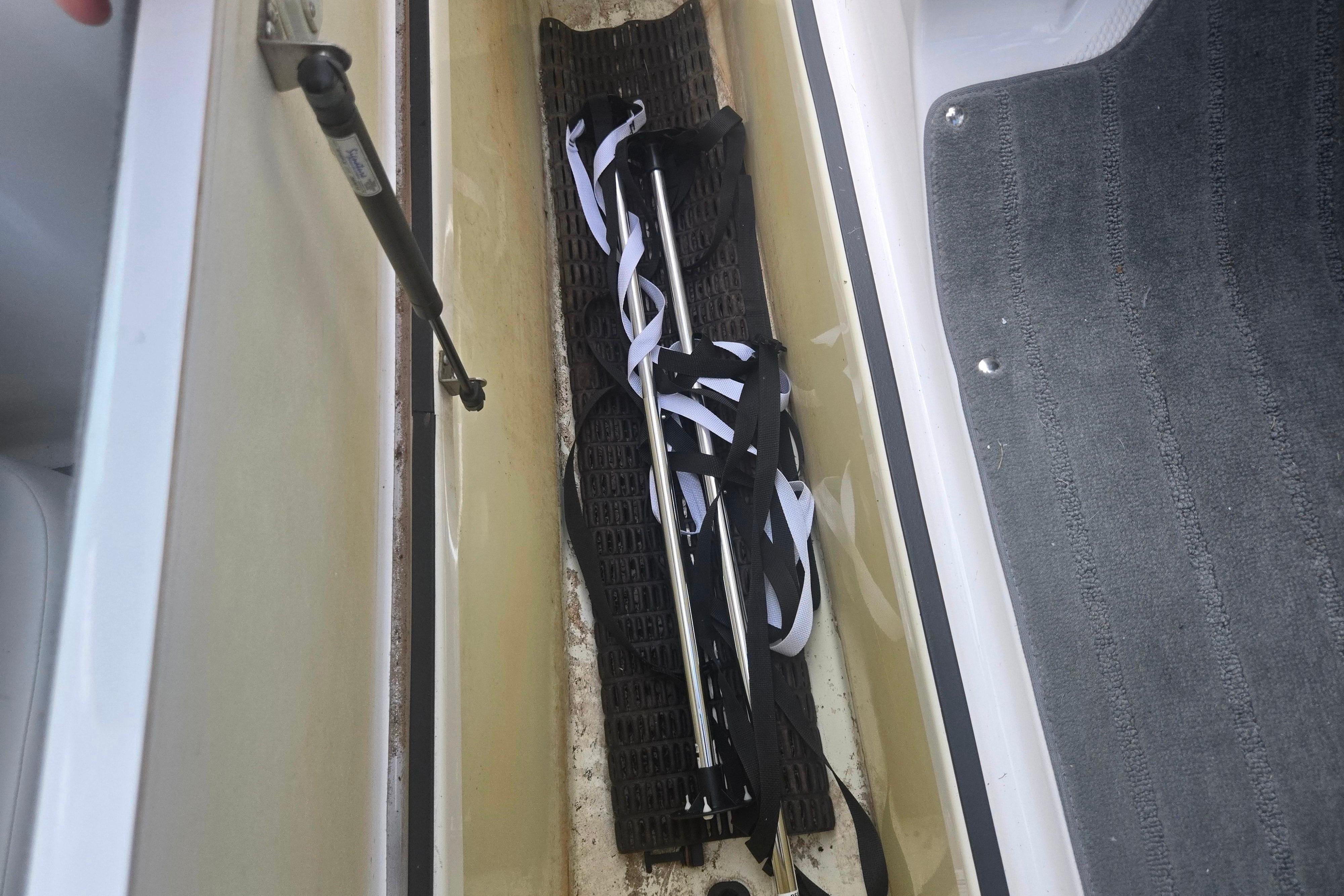 Storage compartment in a 2016 Yamaha Boats AR192, containing poles and straps.