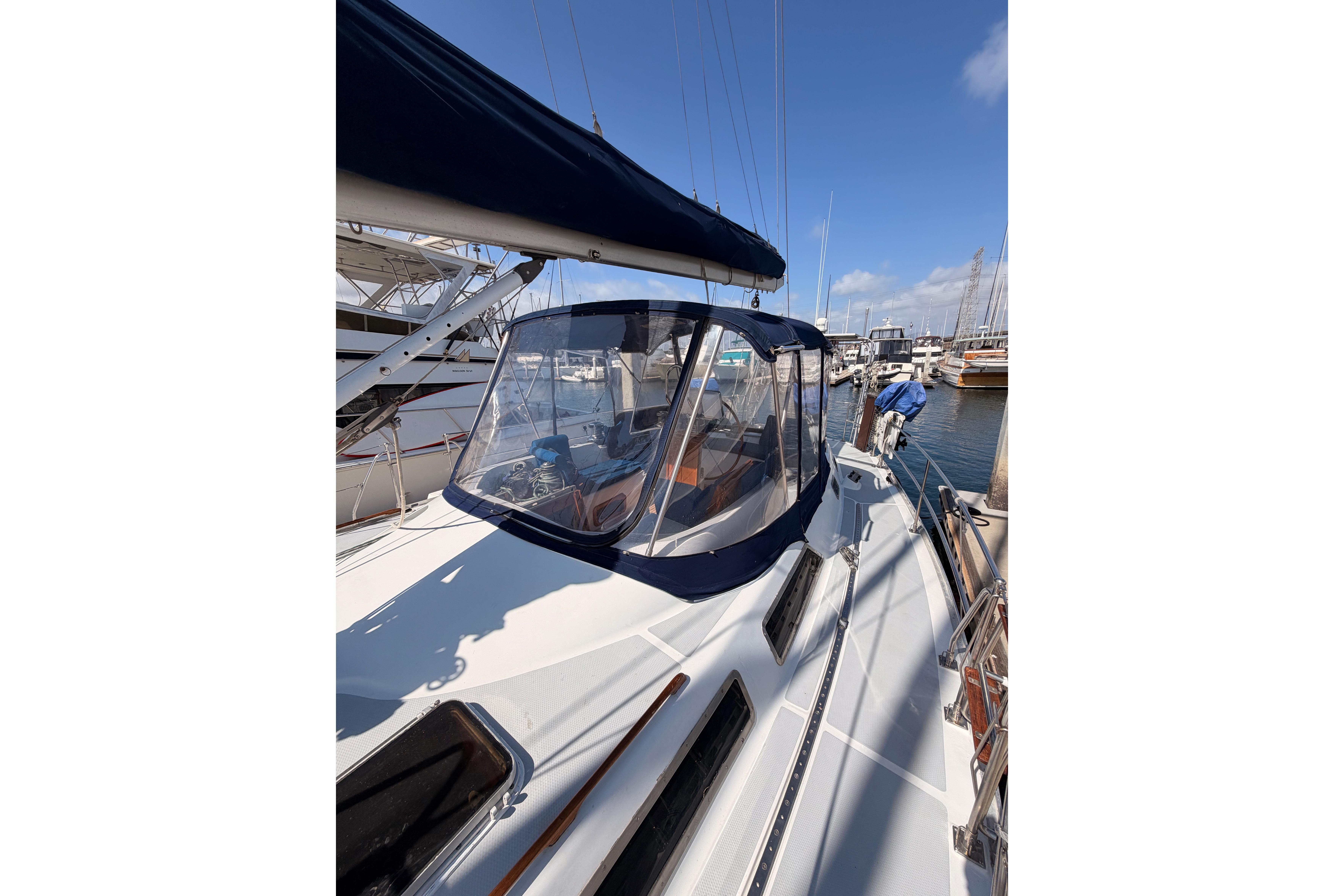 1991 Hylas 51 sailboat docked at marina, featuring sleek design and clear cockpit enclosure.