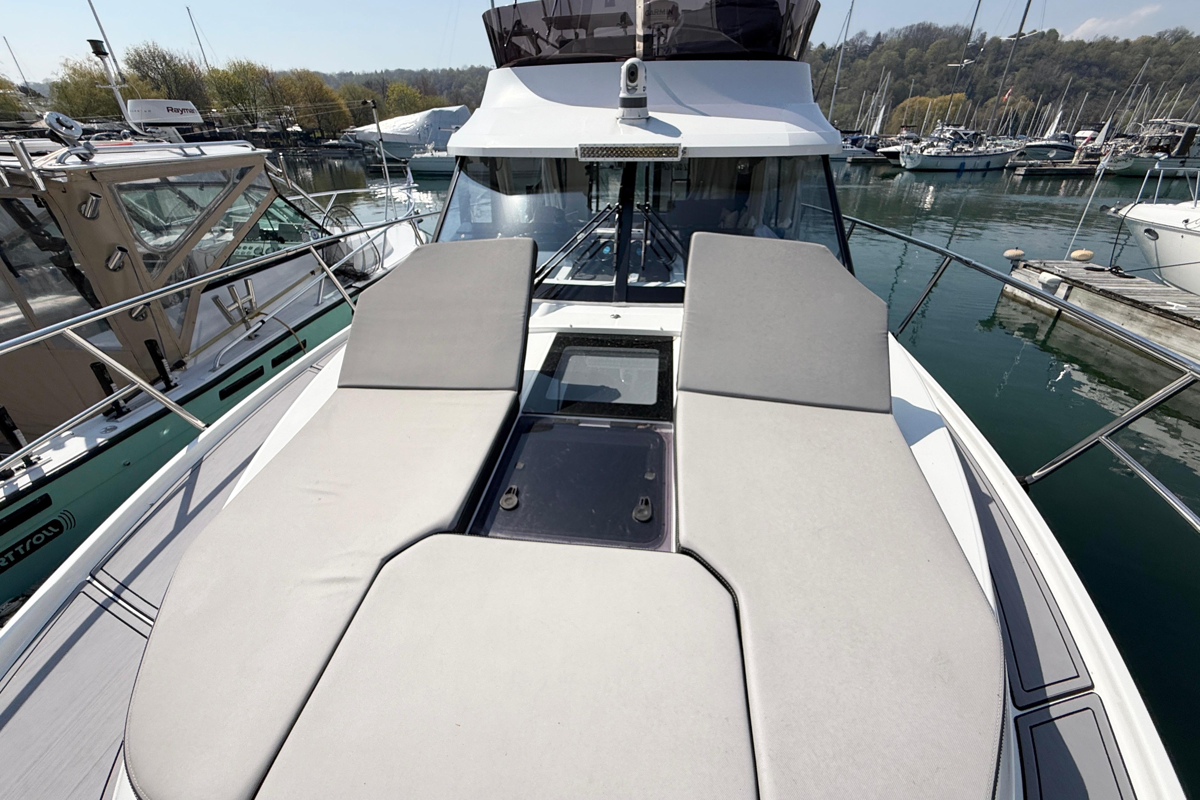 2022 Jeanneau NC 1095 Fly yacht with sunbathing cushions, docked in a marina.
