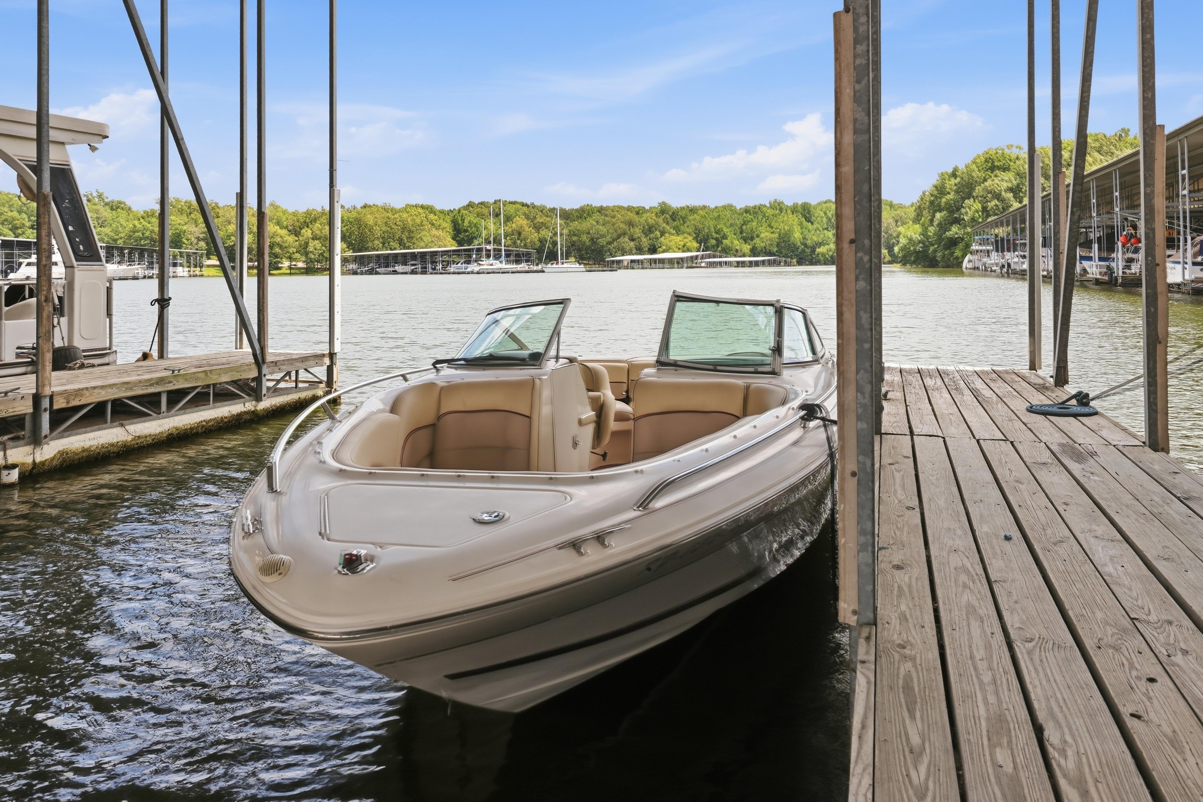 1997 Sea Ray 230 Signature boat docked on a serene lake under a clear blue sky.