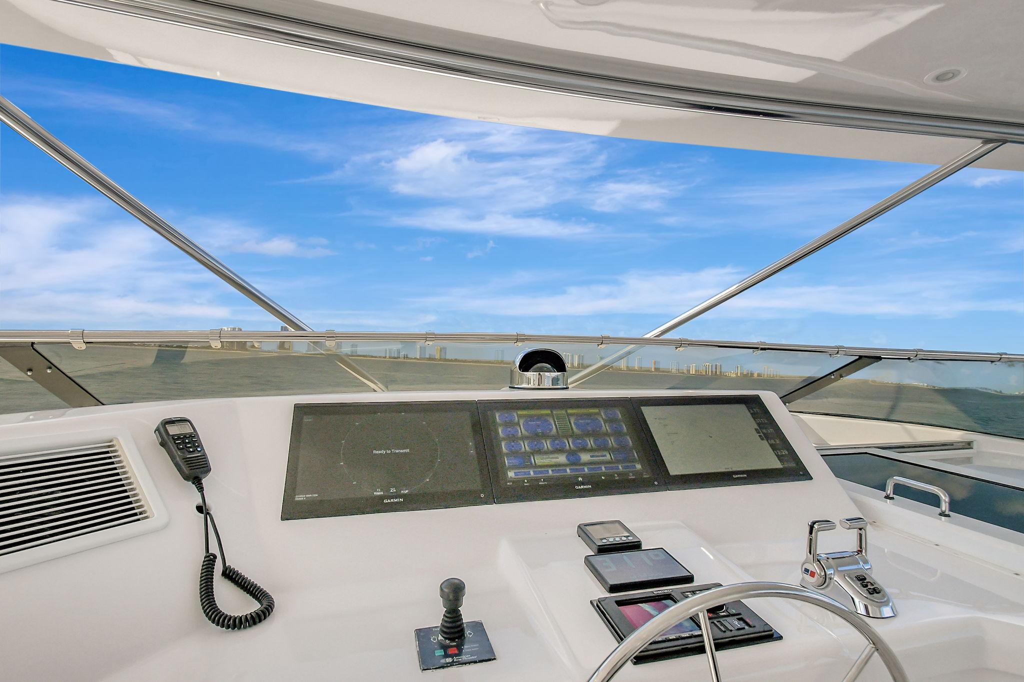 Helm of 2005 Hatteras Semi-Displacement yacht with modern controls and blue sky view.