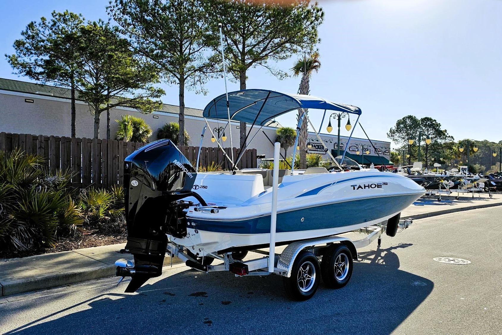 2026 Tahoe 2150 boat on trailer, parked outdoors with trees and buildings in background.
