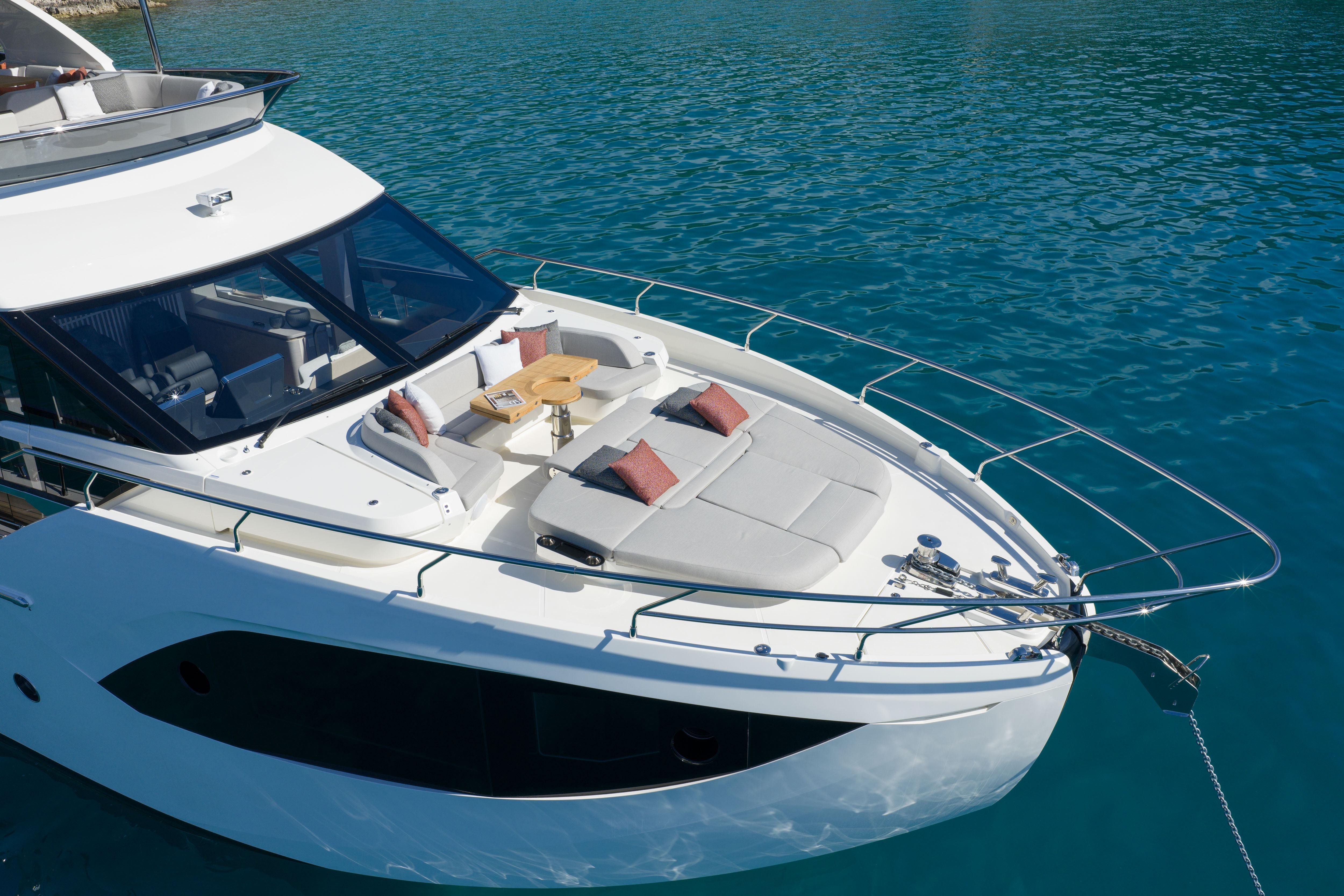 Luxury yacht with sun deck and cushions on calm water.