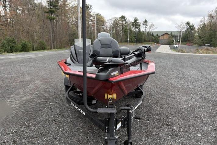 2026 Tracker Pro Team 175 boat on trailer, parked on gravel road with trees in background.